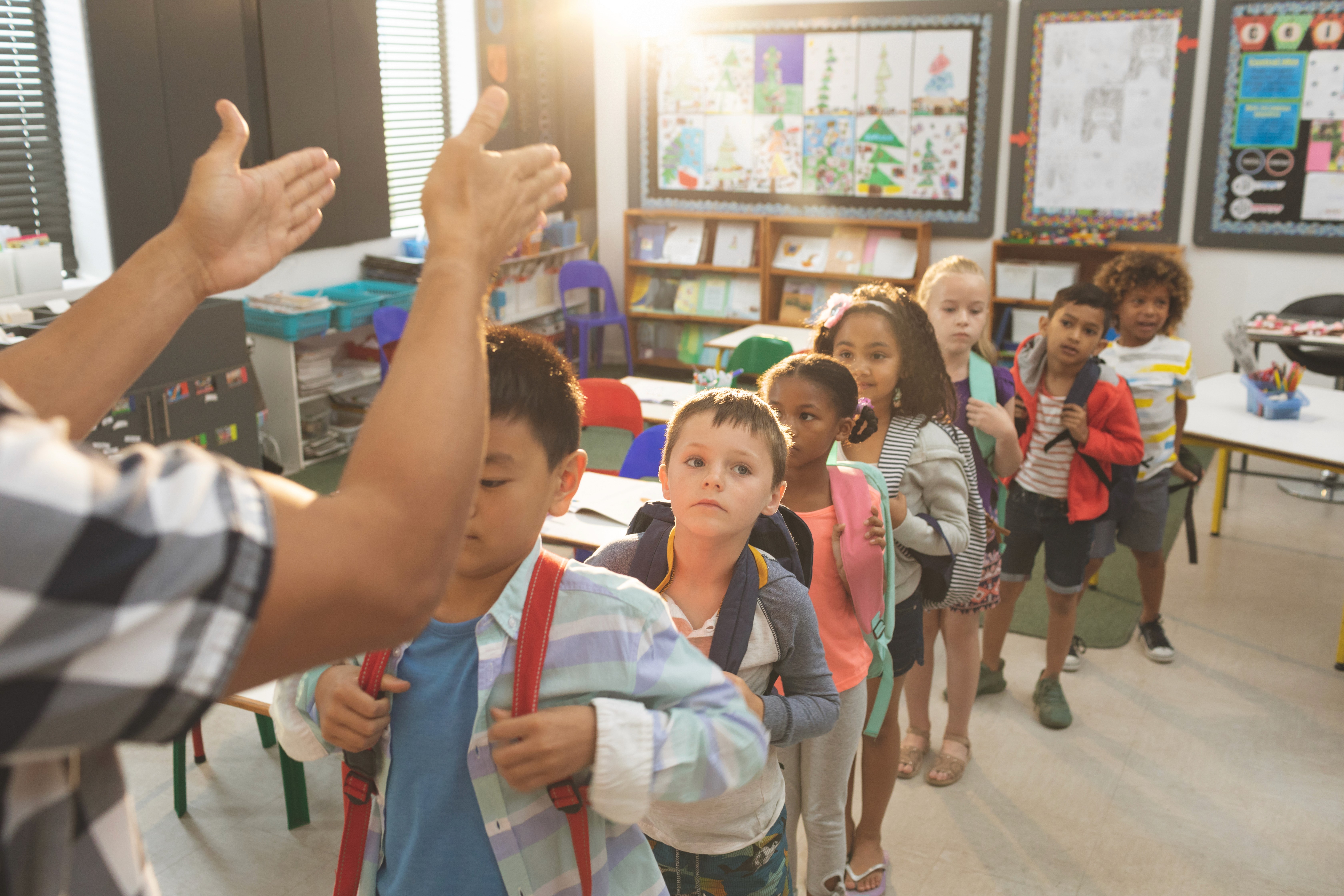 Image of a school classroom where the teacher is guiding students to form a line as they act out a practice drill for emergency response.
