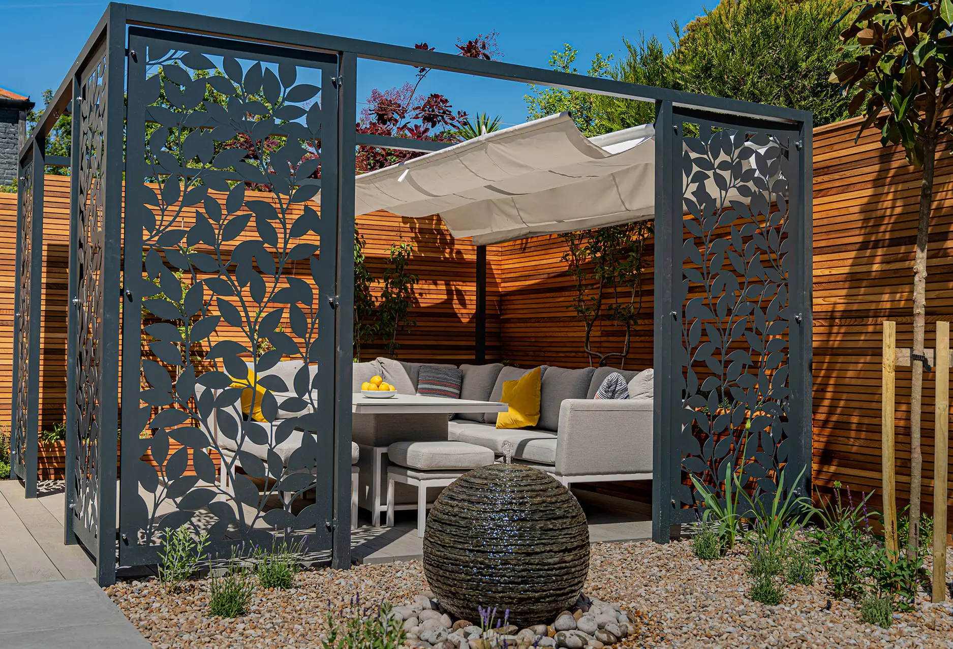 Modern outdoor space with artistic metal gate, wooden accents, and a cozy seating area surrounded by greenery.