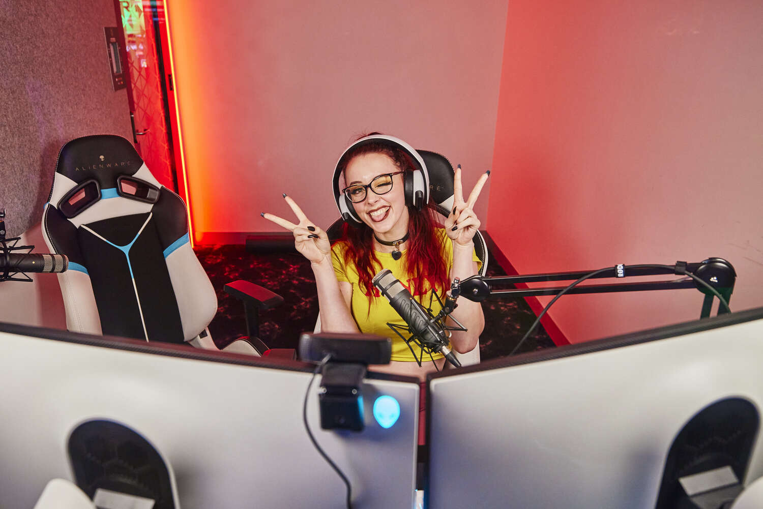 A person sitting in front of a computer with 2 monitor with a headphones on 