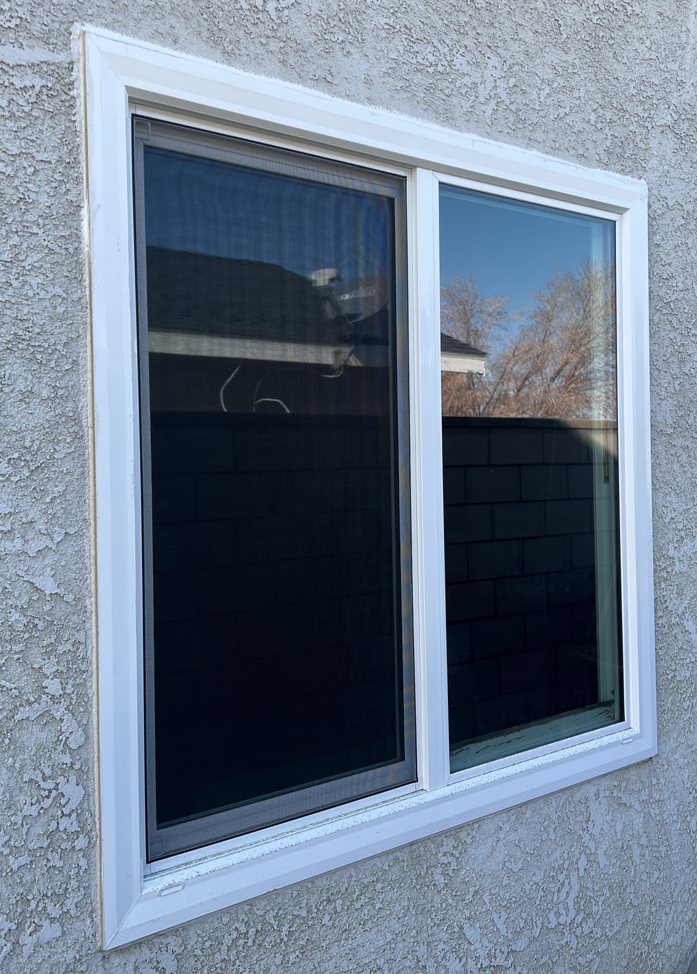 Modern kitchen with a wooden dining table, white chairs, and a hanging light fixture above.
