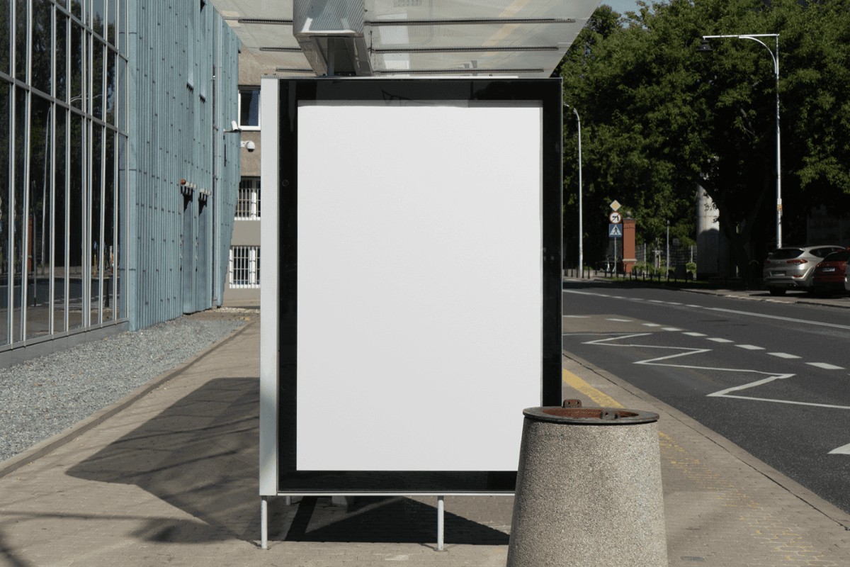 Mockup of a citylight advertisement display at a modern bus stop on a quiet urban street. The sleek design is framed by contemporary architecture and greenery, perfect for showcasing outdoor advertising campaigns.