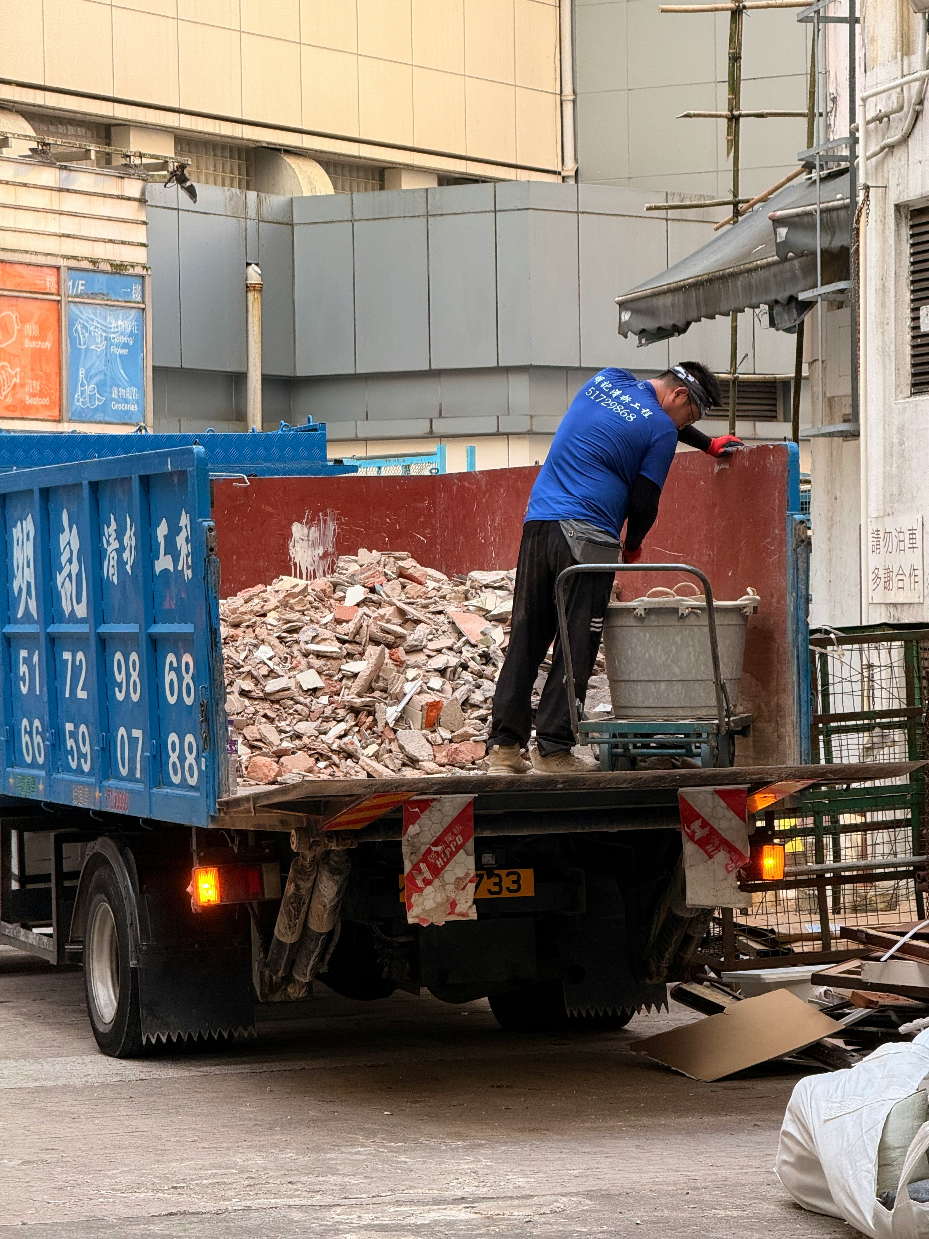 Worker loading debris into a blue truck
