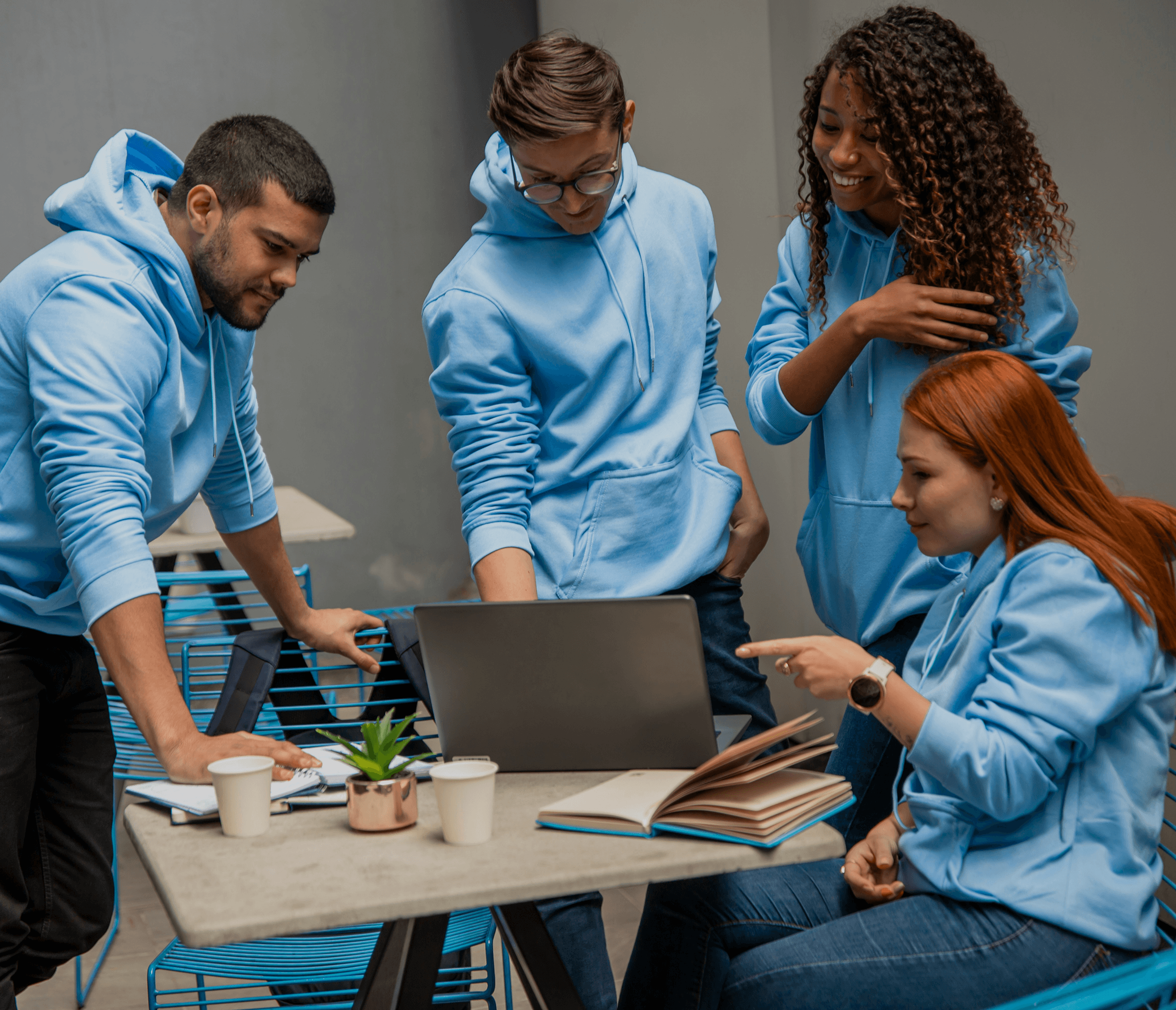 Our people in light blue hoodies putting their hands together outside, symbolizing teamwork and unity.