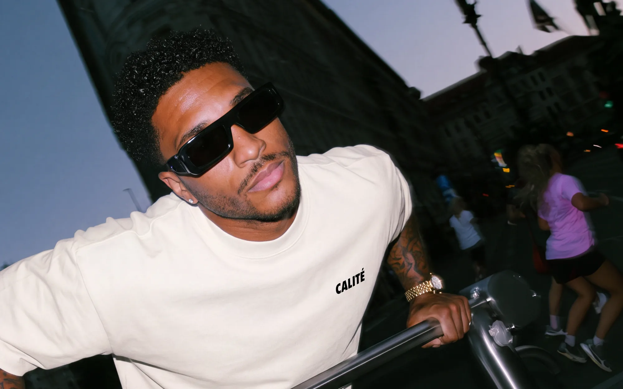Calité: Model mit Sonnenbrille im Calité-Shirt am Geländer, Straßenszene