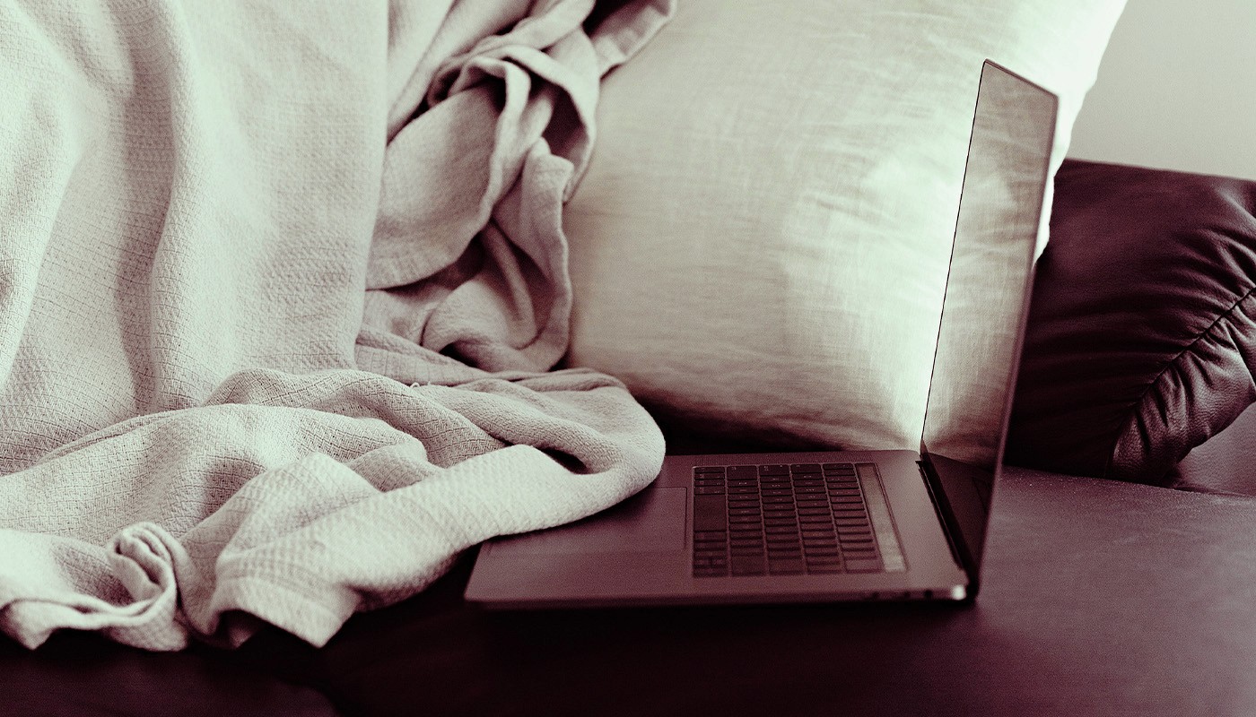 Open laptop on a sofa at cosy home