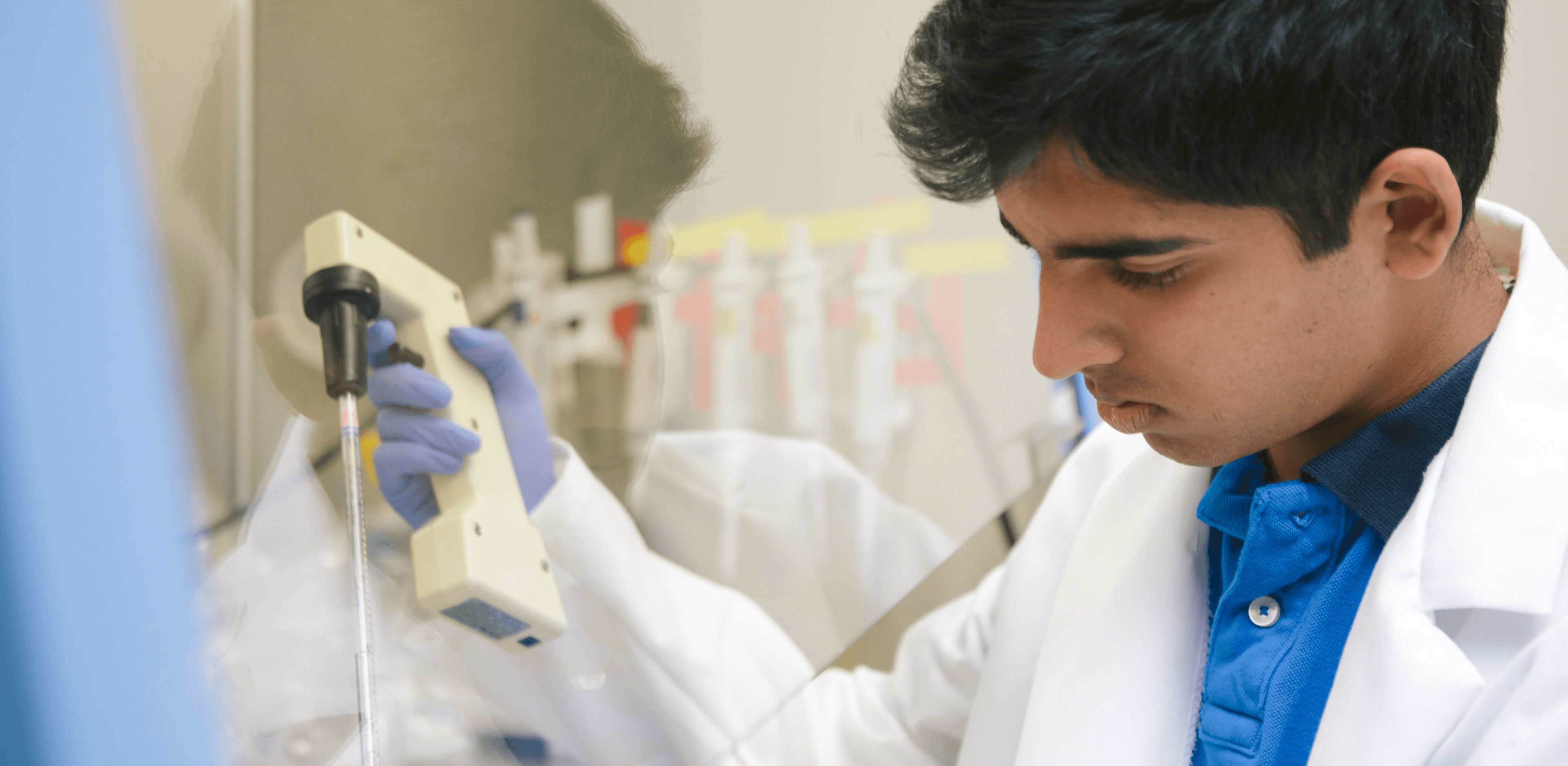 Young Indian researcher using lab equipment for scientific experiment in pharmaceutical lab