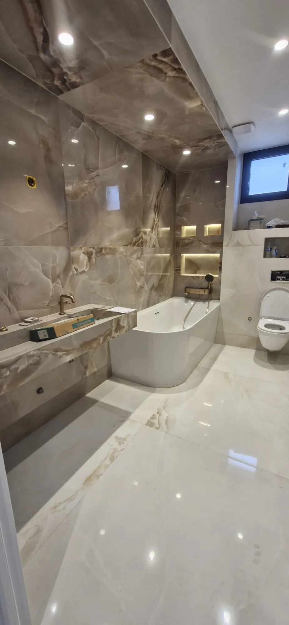 Salle de bain carrelée en grand format effet marbre autour d'une baignoire îlot