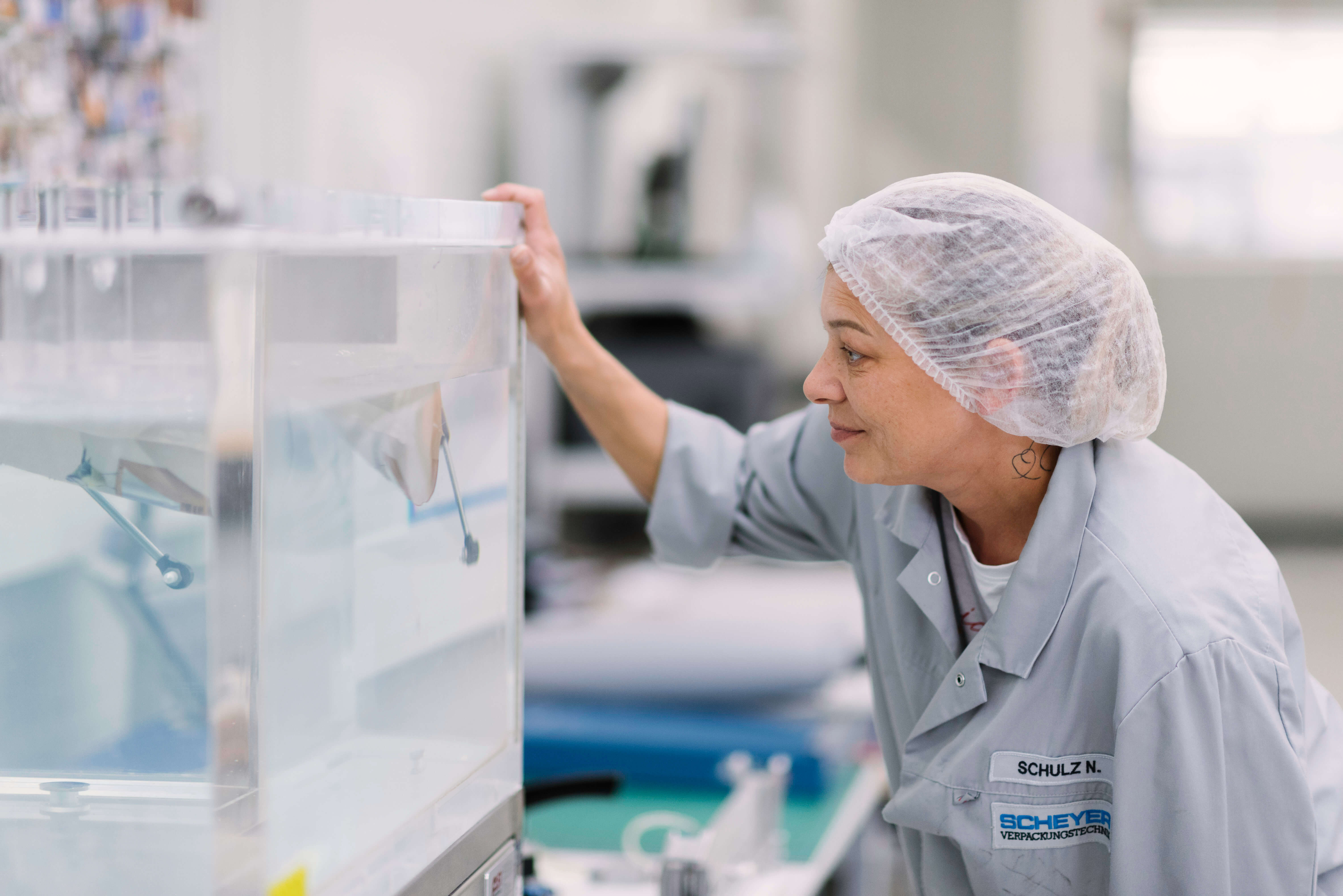 Scheyer employee performing quality tests on packaging materials, using a tank filled with liquid in a controlled environment.