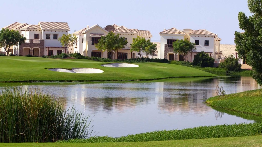 A scenic view of Redwood Park golf course featuring houses and a tranquil pond.