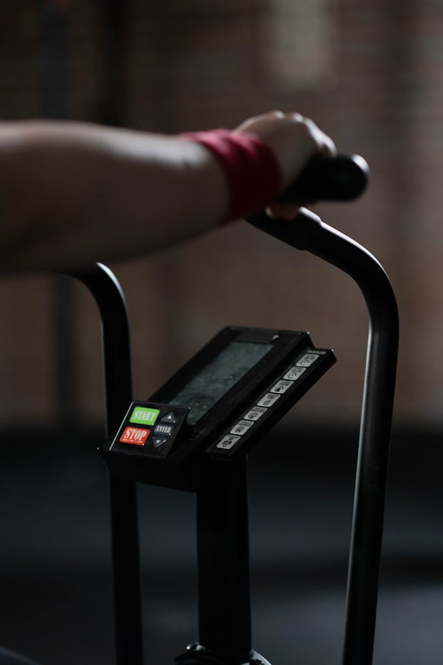Close-up on a technician's hands repairing the belt drive system of a commercial spin bike.