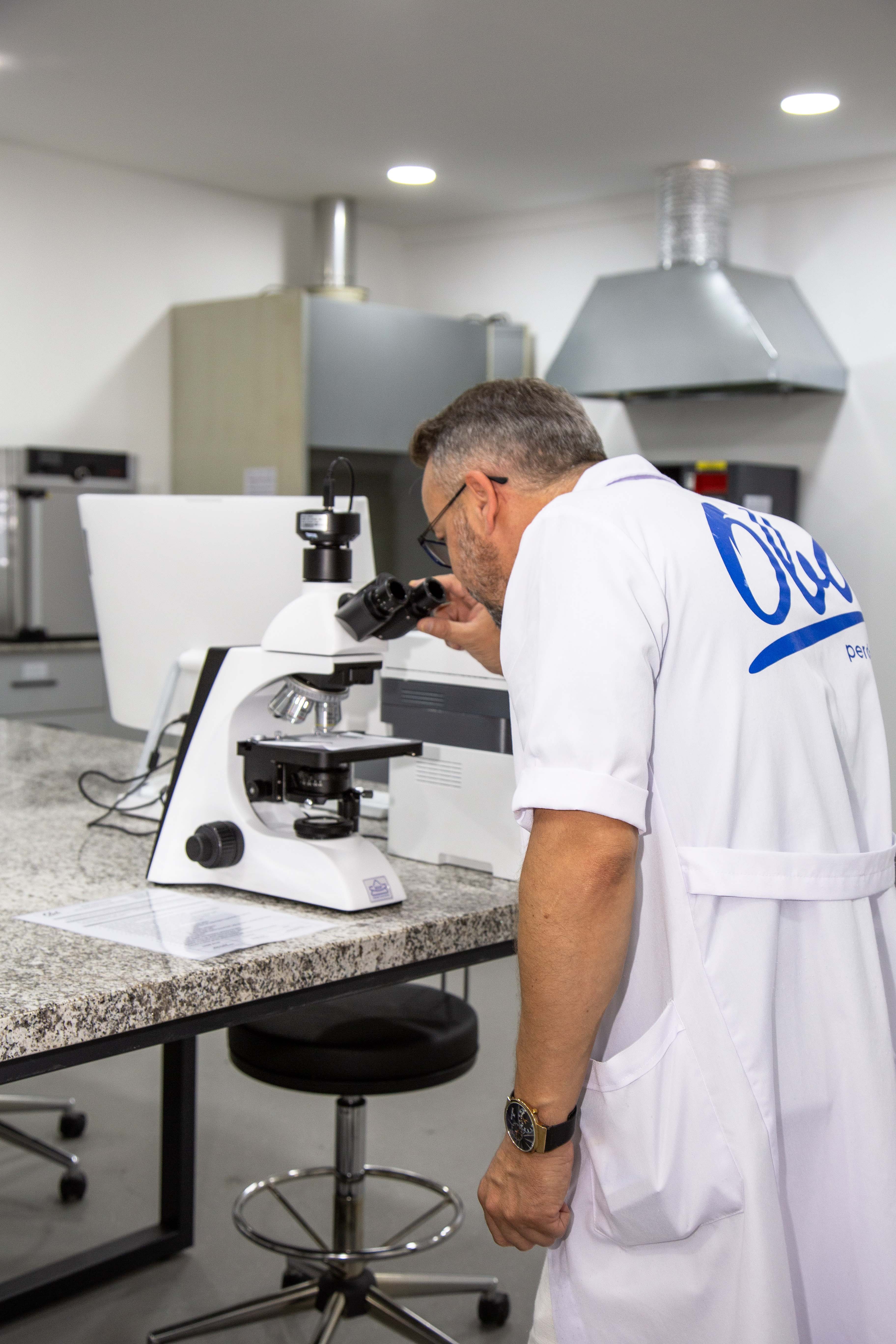 Man with tousled hair sitting at a cluttered desk in a dimly lit room. Warm, orange lighting creates a moody and contemplative atmosphere.