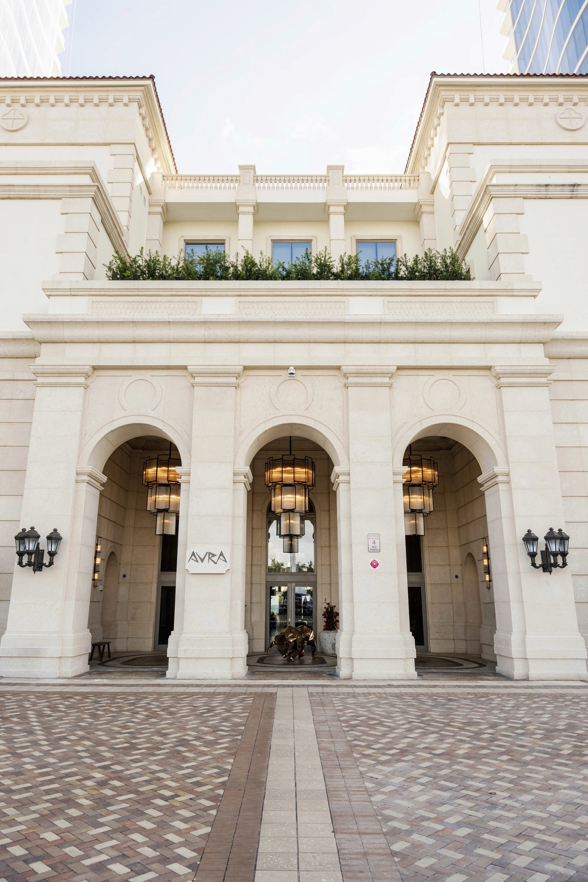 Entrance of a grand building featuring arched doorways and decorative elements above, set against a clear sky.