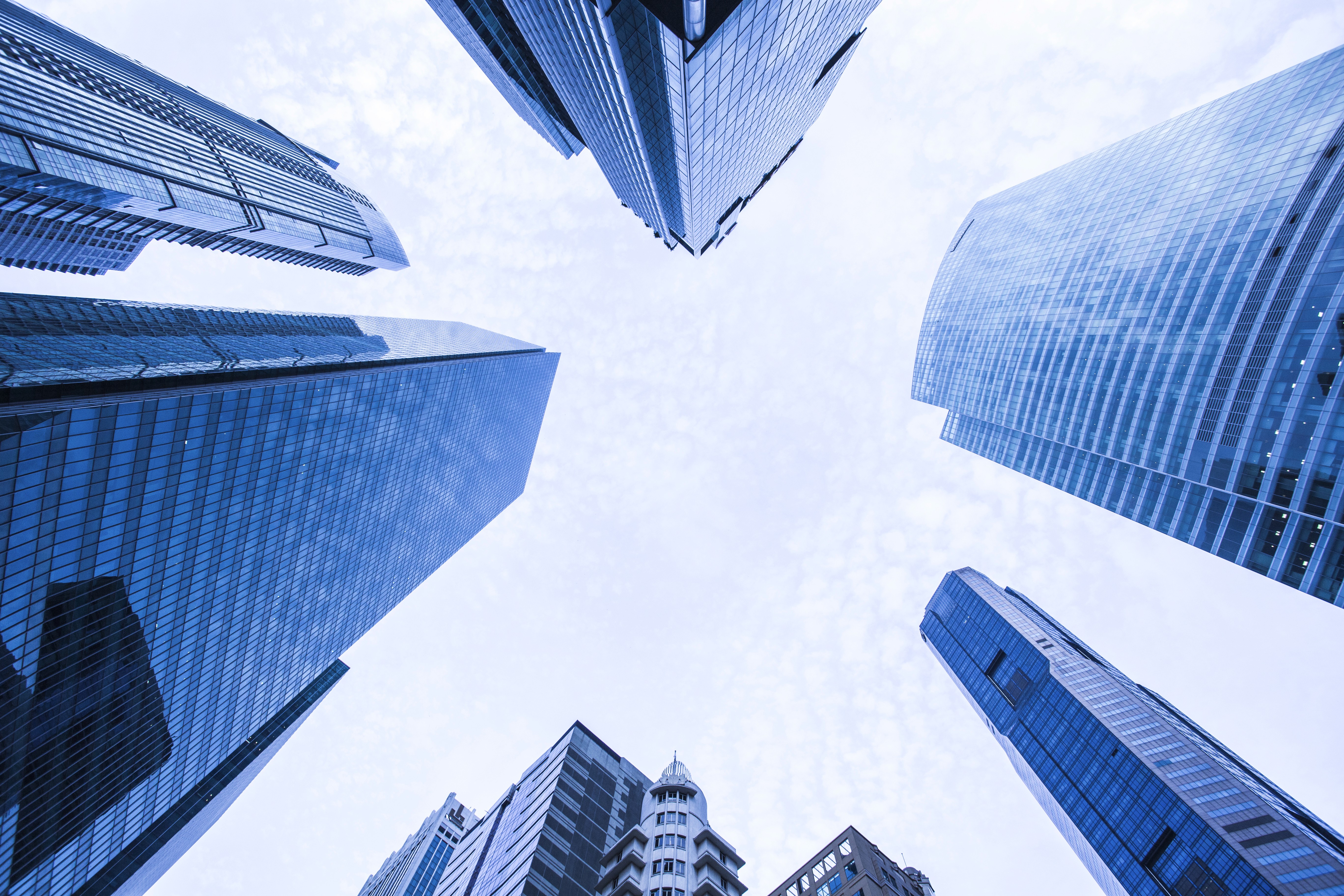 Close-up portrait of a person wearing a gray insulated hooded jacket with the hood up, showing their face framed by the hood against a light background.