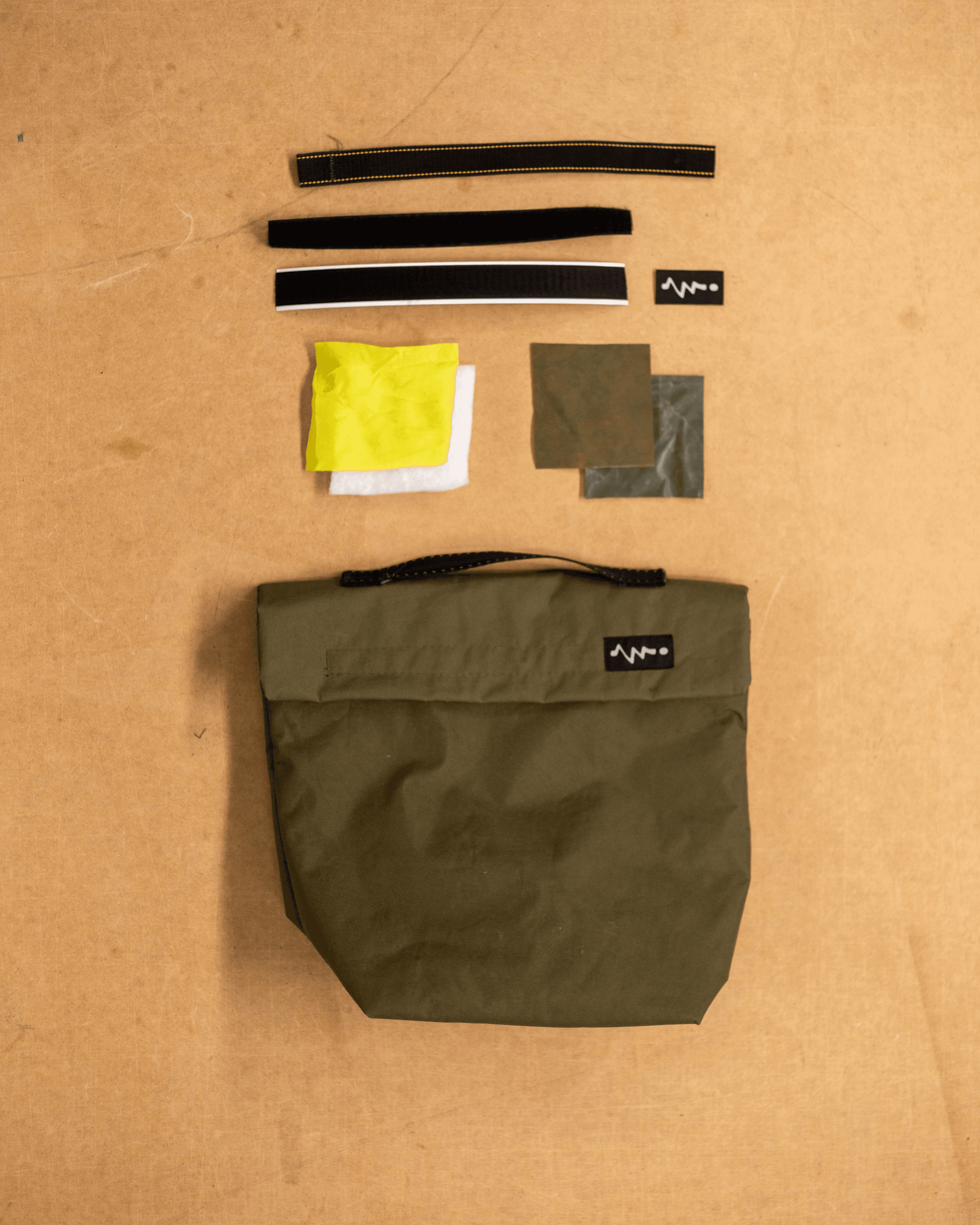 Flat lay showing components of an upcycled protective bag, made from salvaged textiles and industrial offcuts.