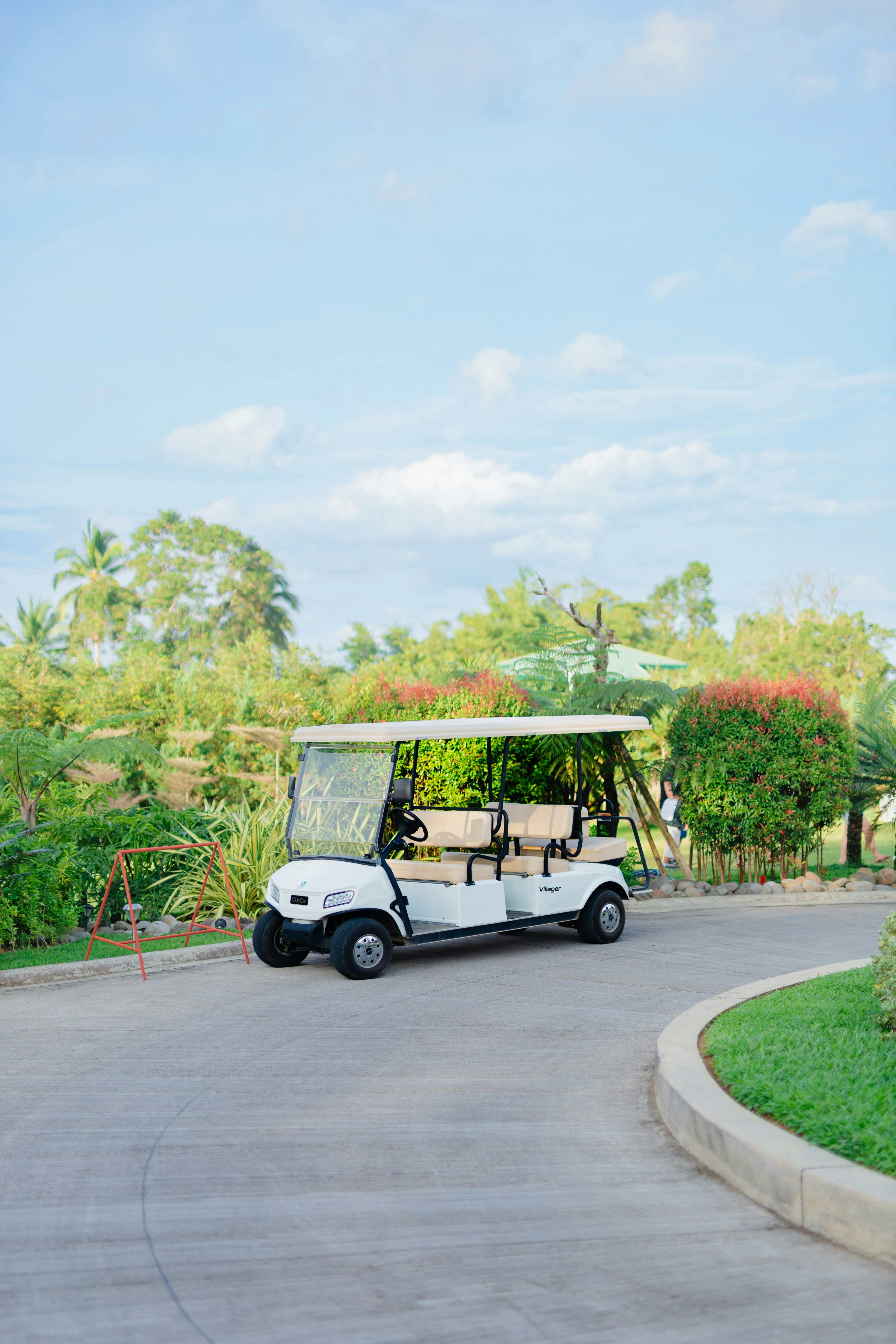A white golf cart parked on a paved path.