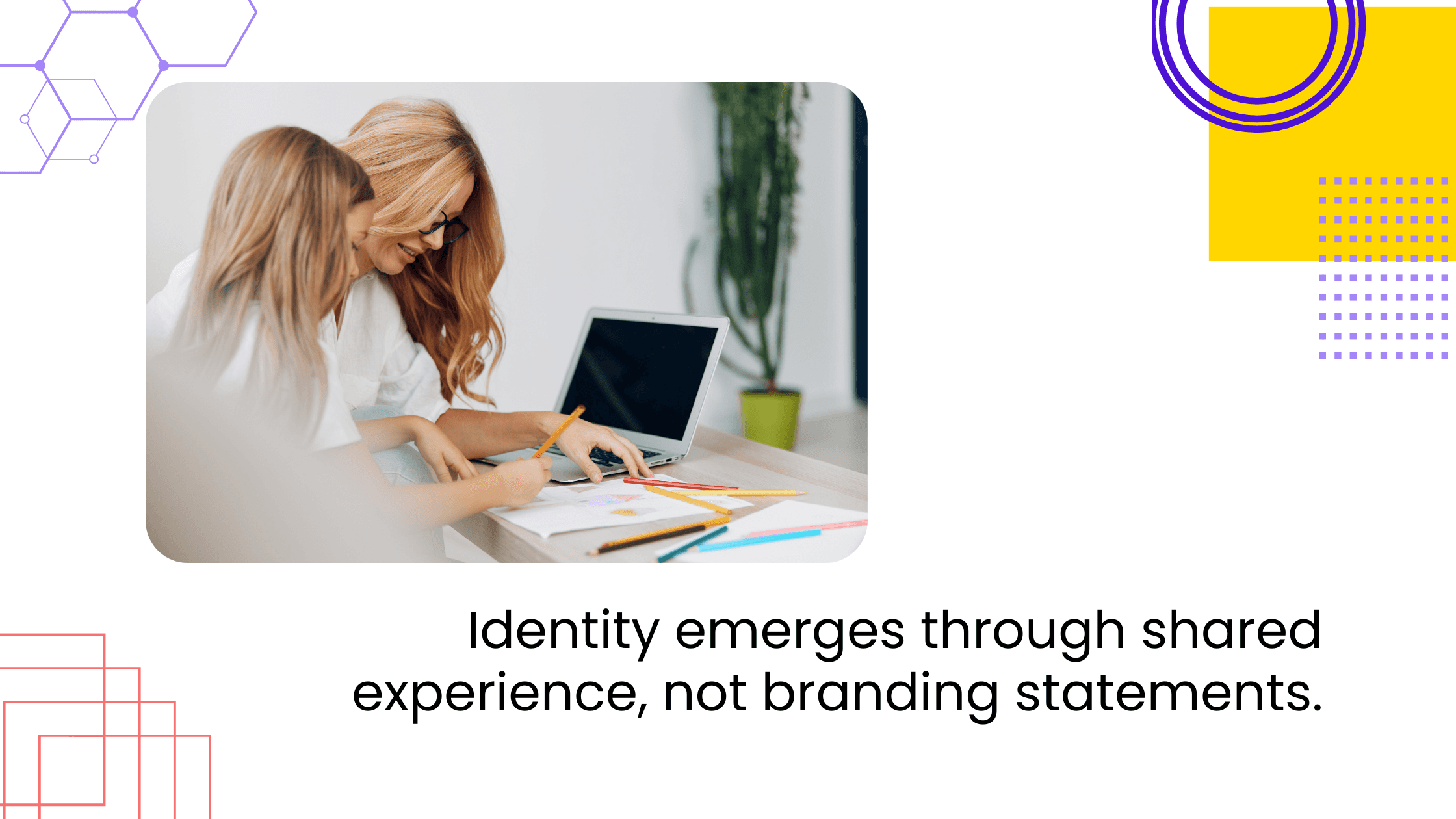Two women working together at desk reviewing notes and laptop, with headline about identity through shared experience.