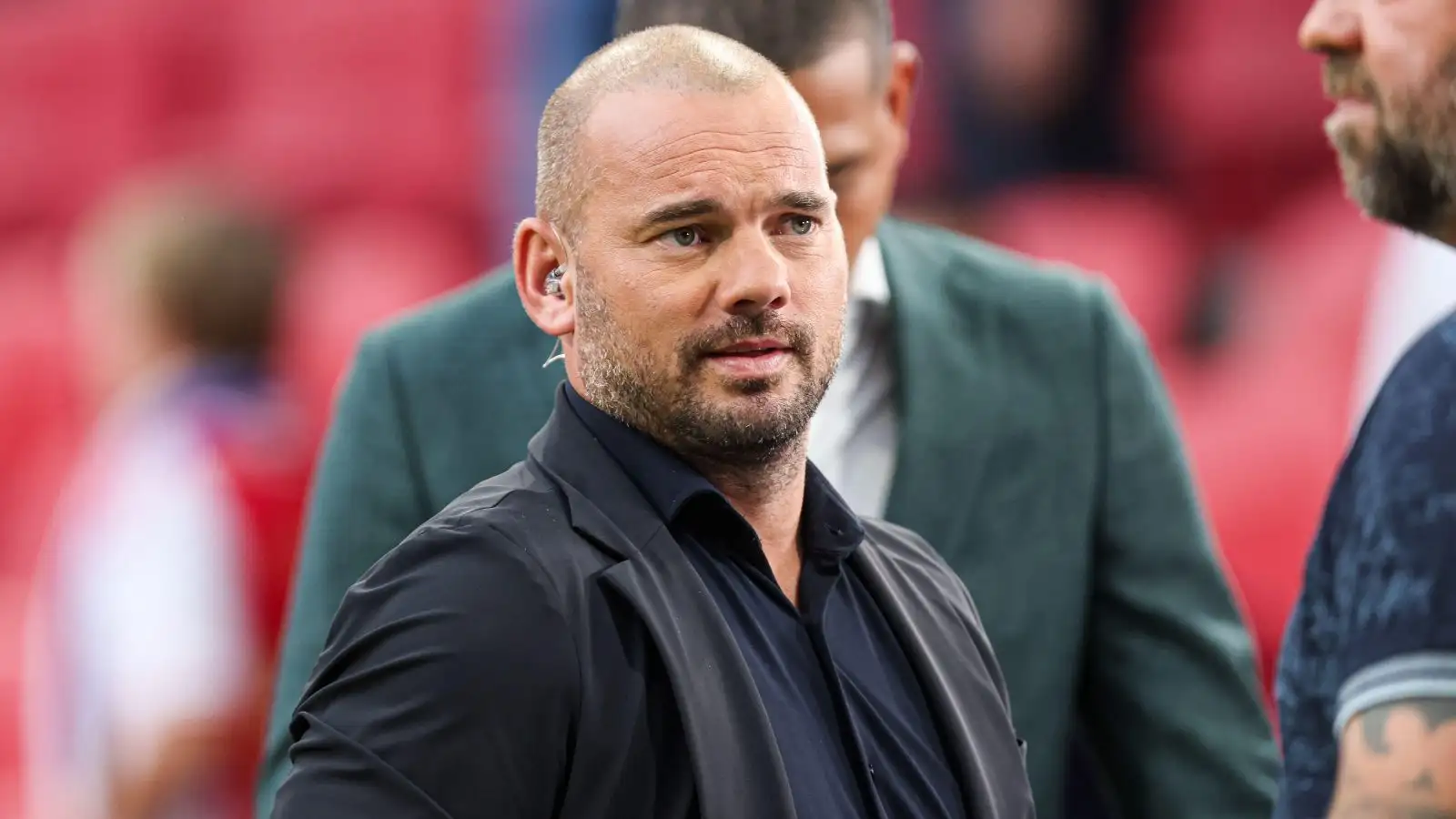 A serene outdoor seating area with two chairs, surrounded by lush greenery and a glassed-in structure.