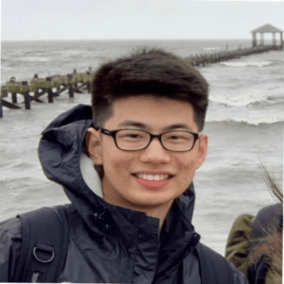 Man in denim jacket smiling outdoors.