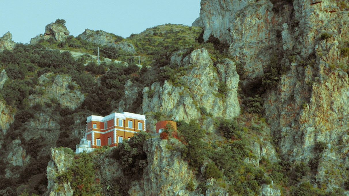 Bright red and white villa nestled against dramatic rocky cliffs near Rome, Italy, photographed by Janice Chen.