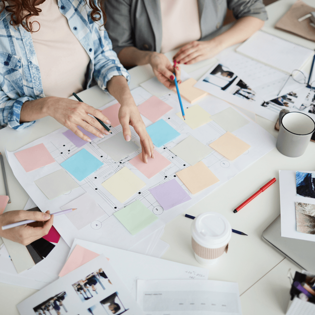 A team gathers around colourful notes and diagrams on a table