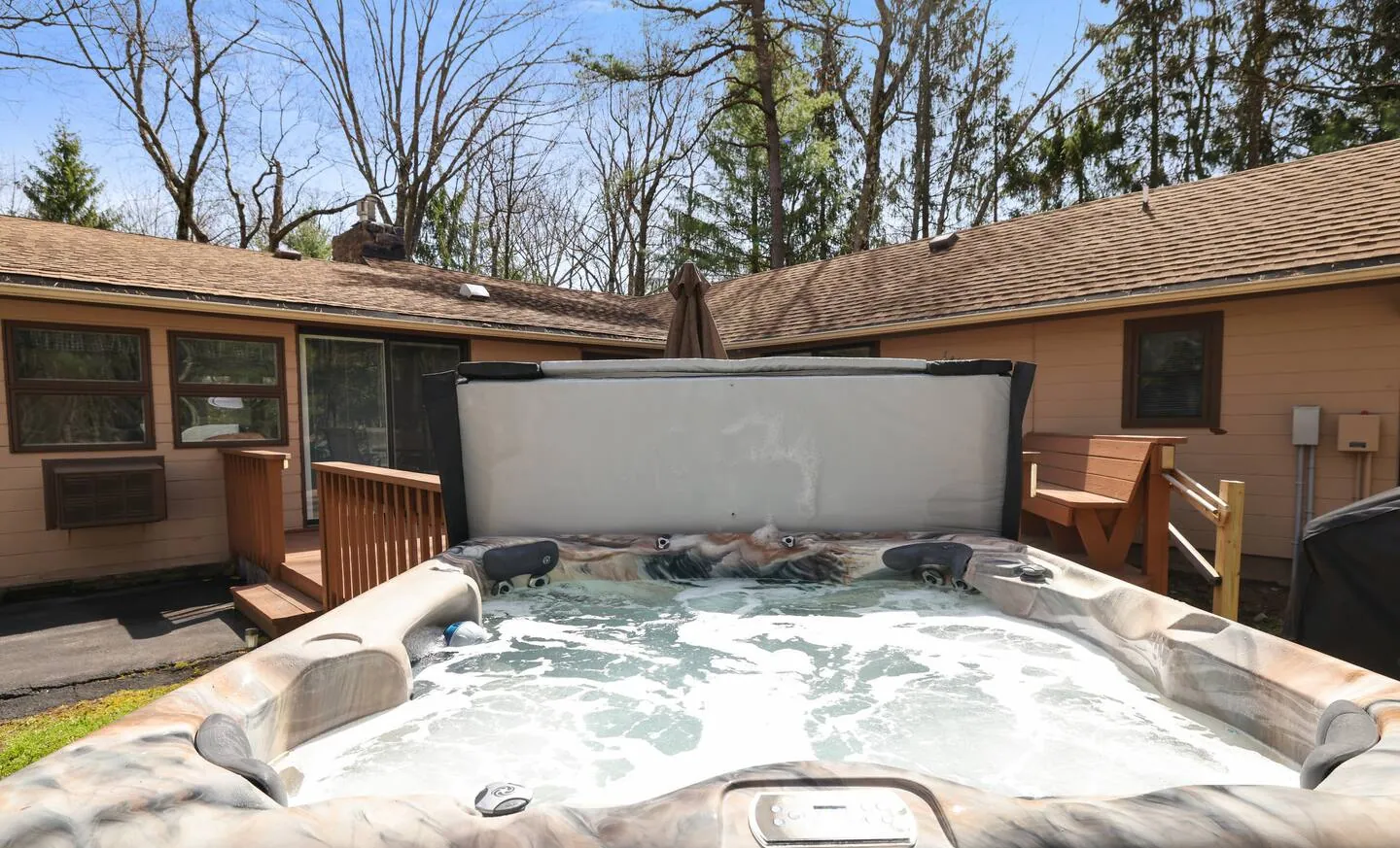Six-person hot tub with cover lifted by the back patio at Relax in Style, Lake Harmony, PA