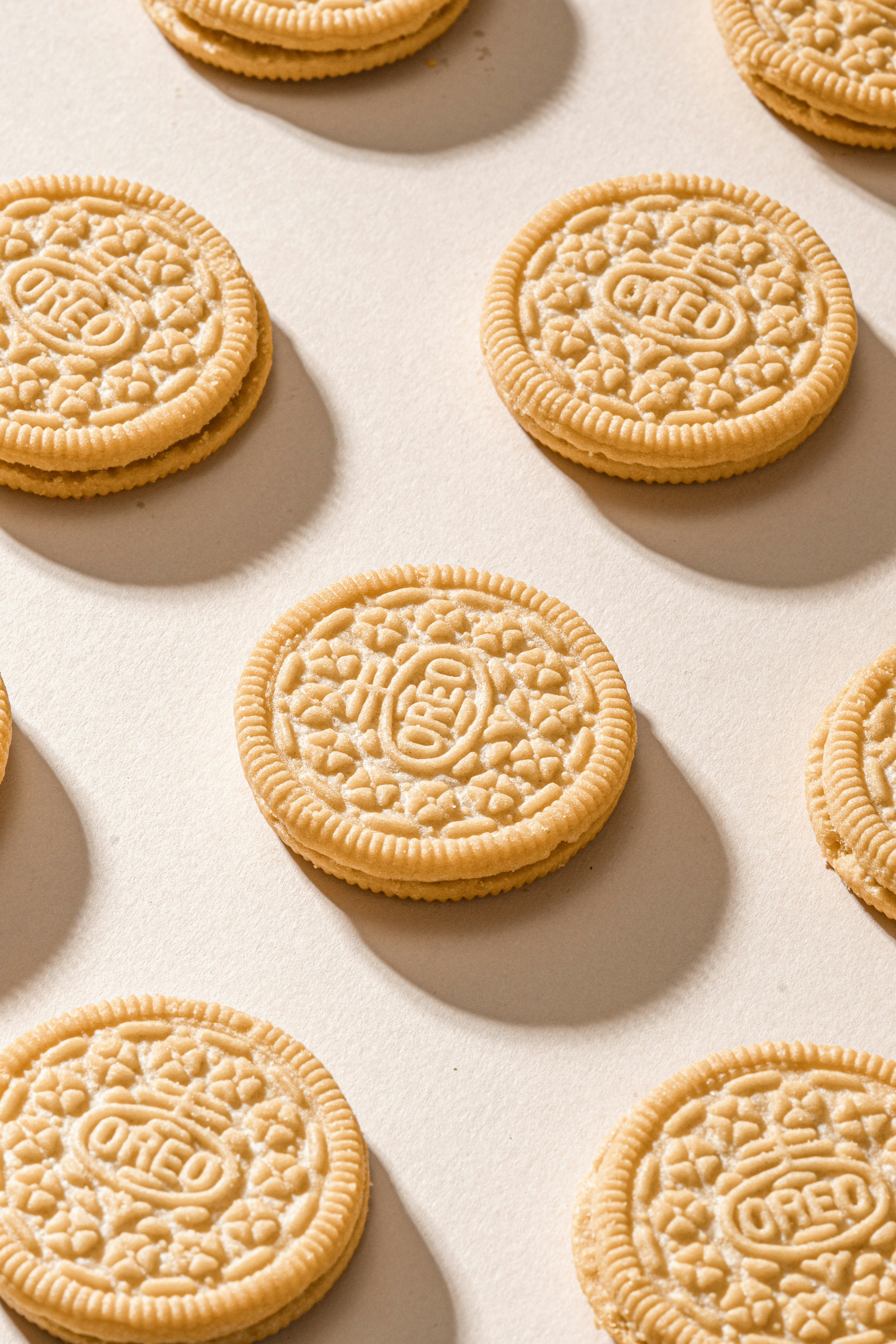Several golden oreo cookies arranged on a light surface.