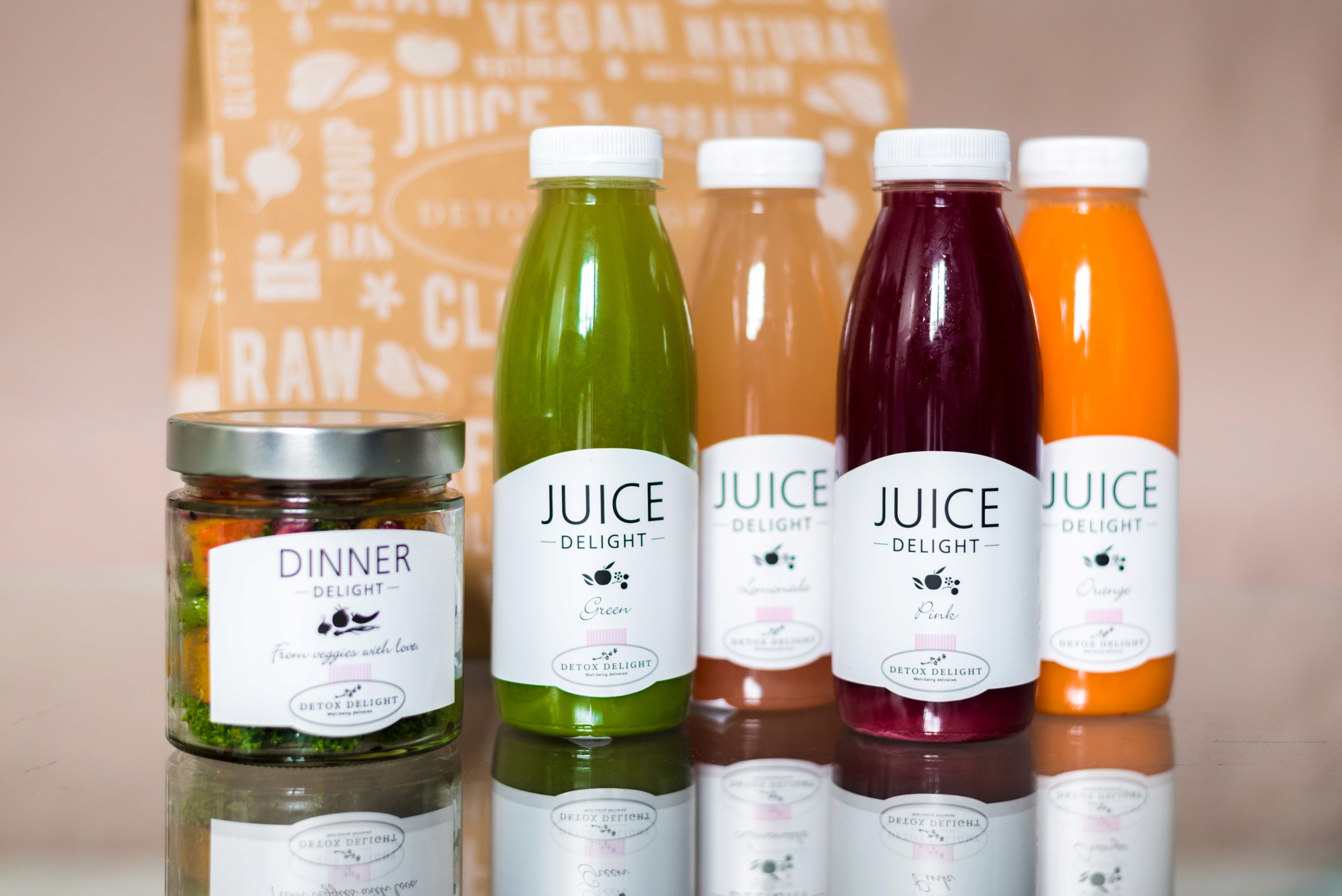 Vibrant rows of fresh green, yellow, red, and orange juices display on a rustic wooden surface under bright natural light.