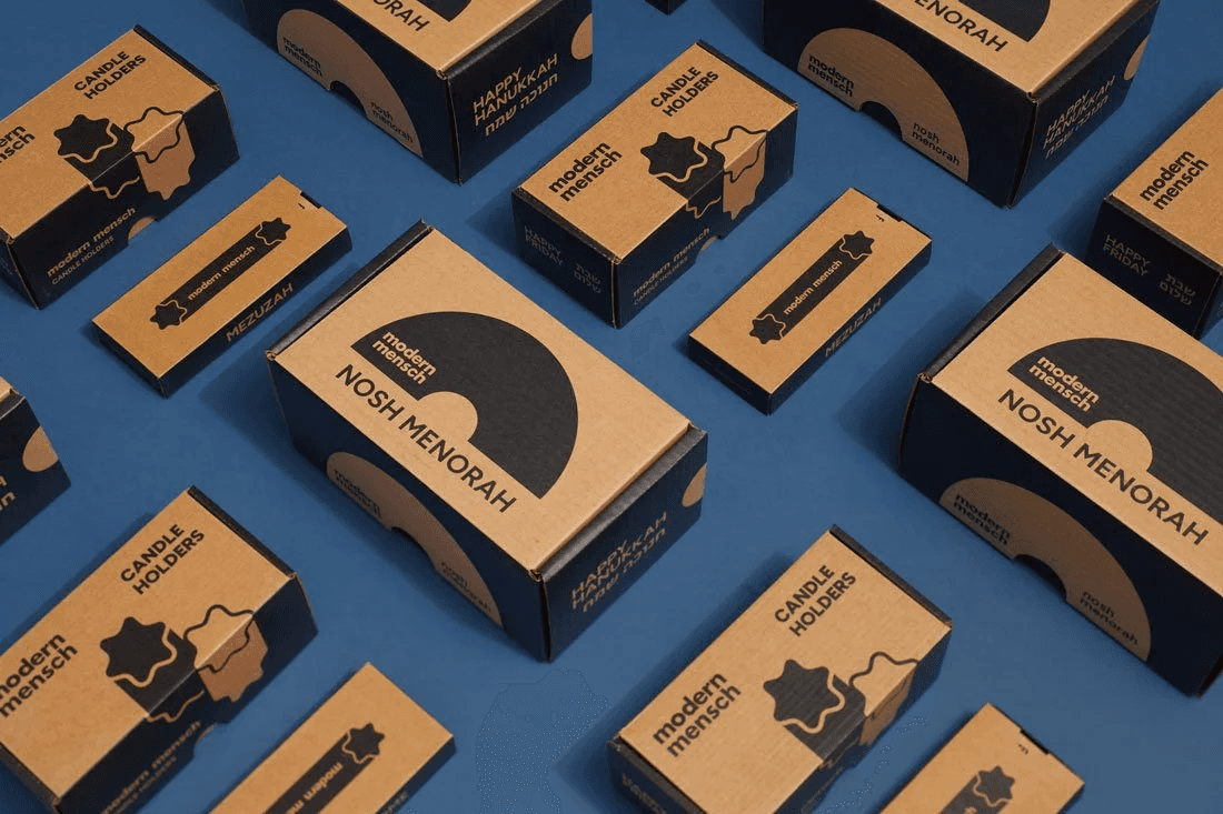 Modern Mensch Nosh Menorah and candle holder packaging arranged on a blue background