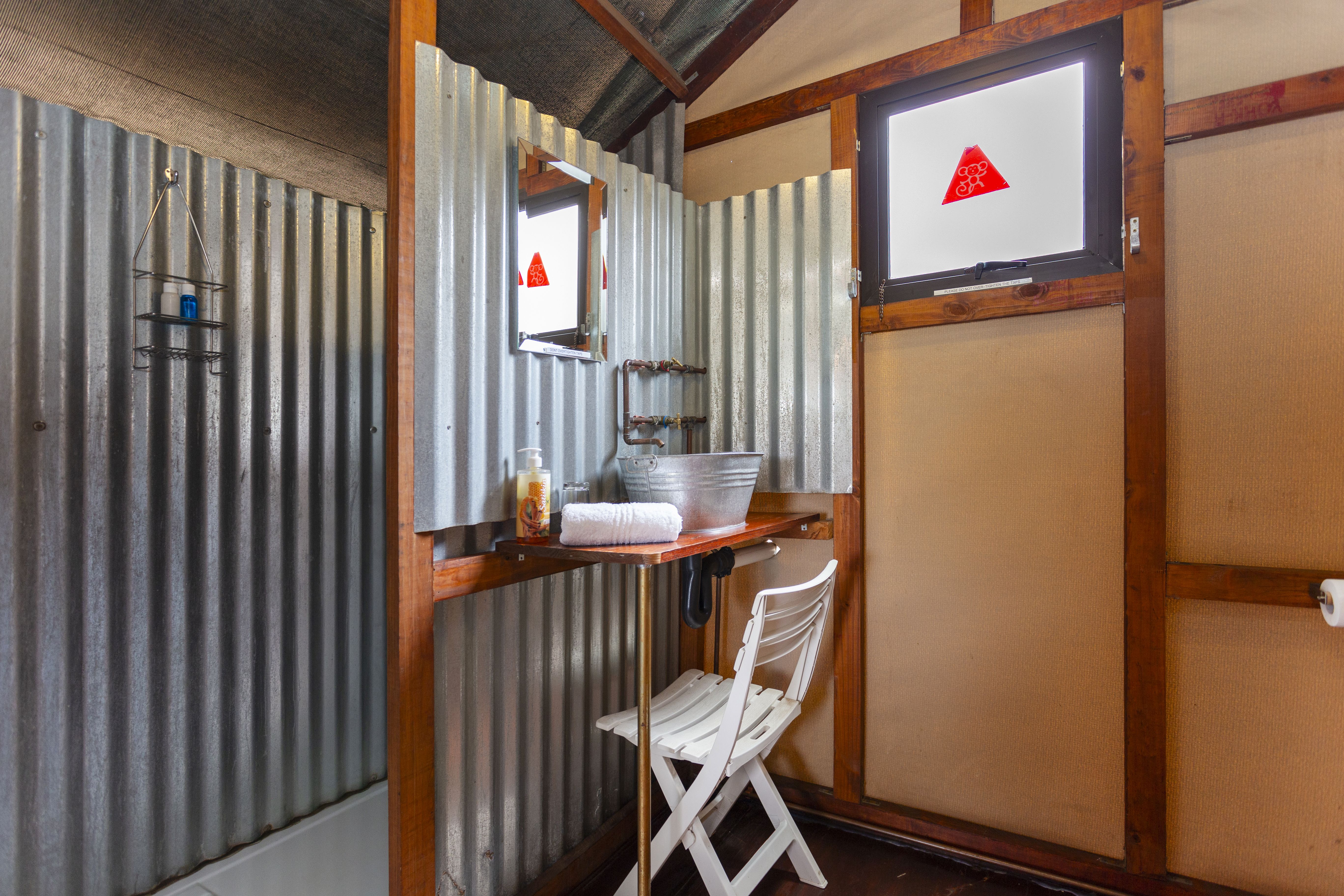 Kilimanjaro Elephant Ride, Arusha, Tanzania. En kvinna sitter och läser utanför ett tält uppsatt i vildmarken.