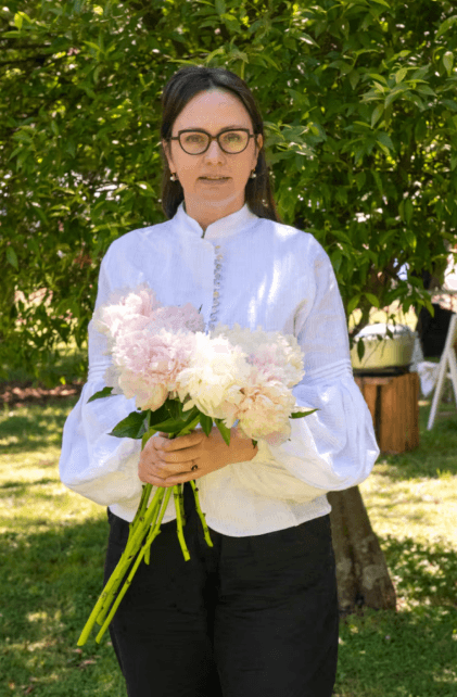 Irina Khatsernova sosteniendo peonías en jardín — creadora floral argentina especializada en flores naturales y arte vegetal.