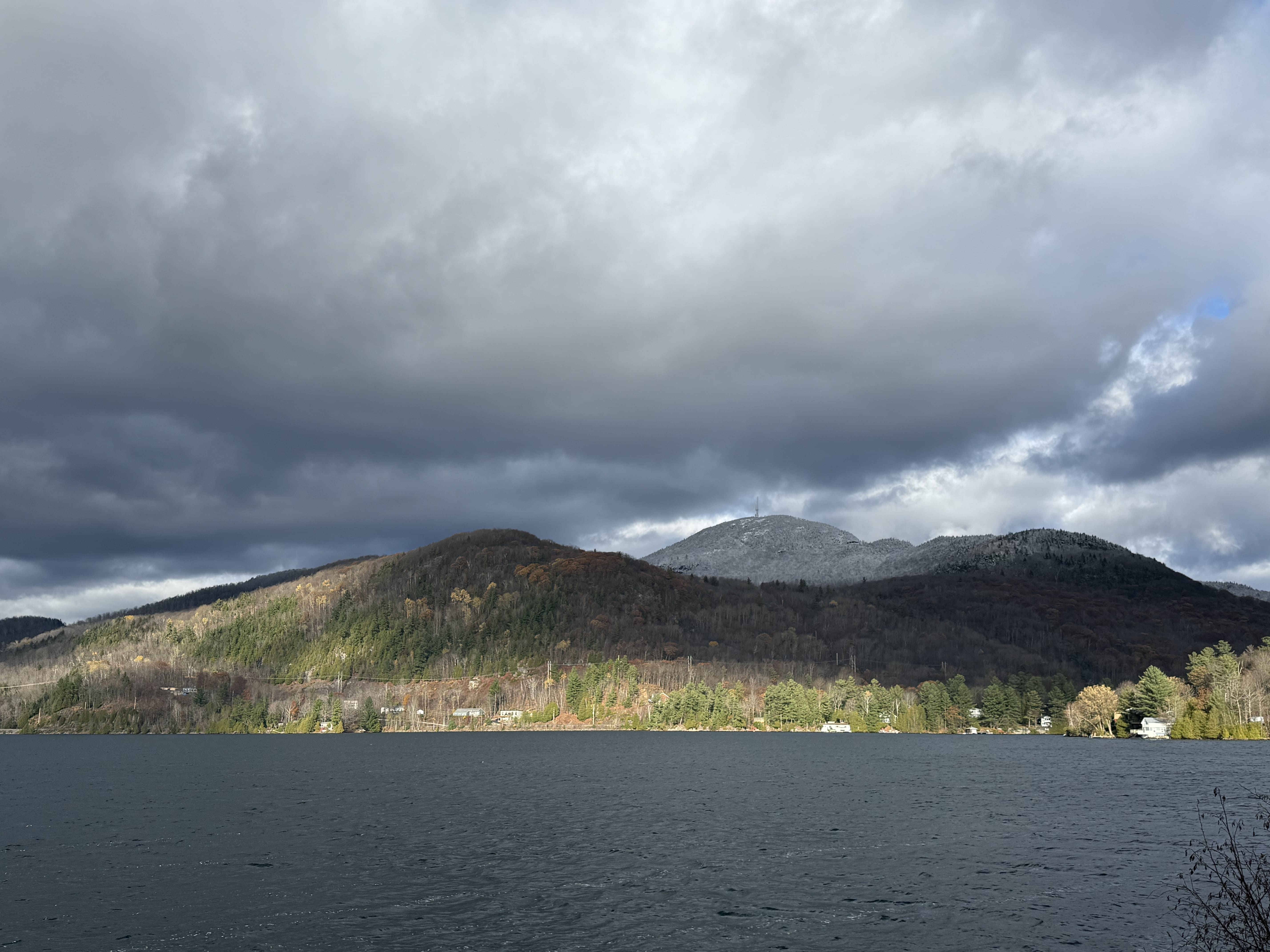 Vue panoramique du lac Orford entouré de collines boisées sous un ciel bleu clair, à Austin en Estrie, Québec.