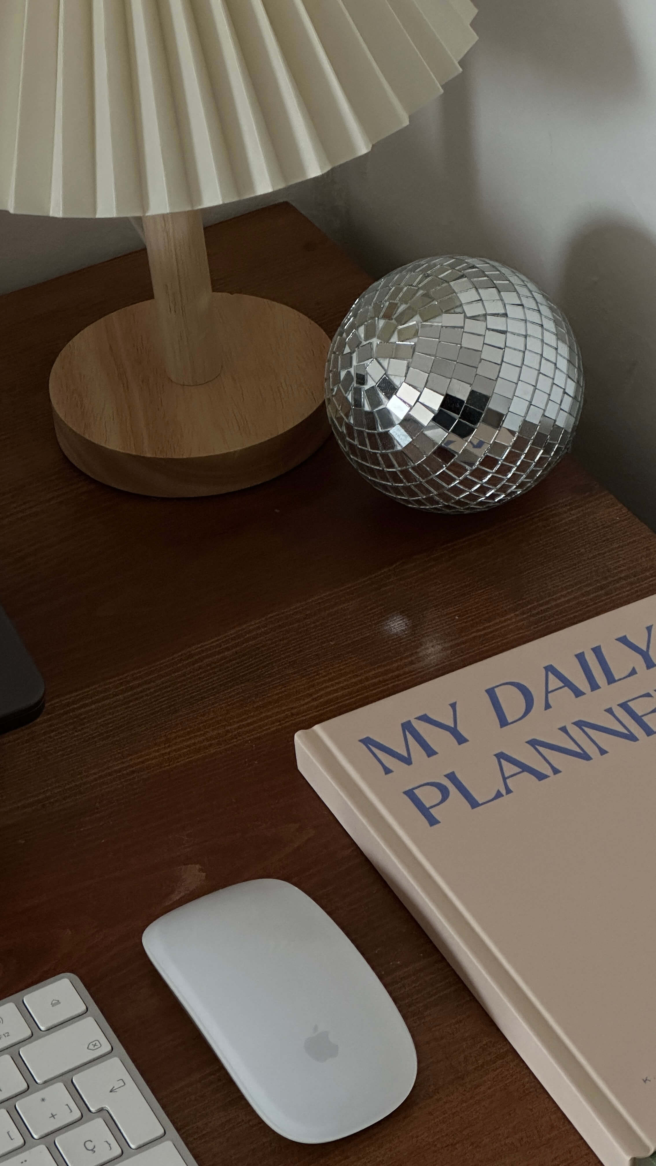 a desk with a disco ball, planner, mouse, and keyboard