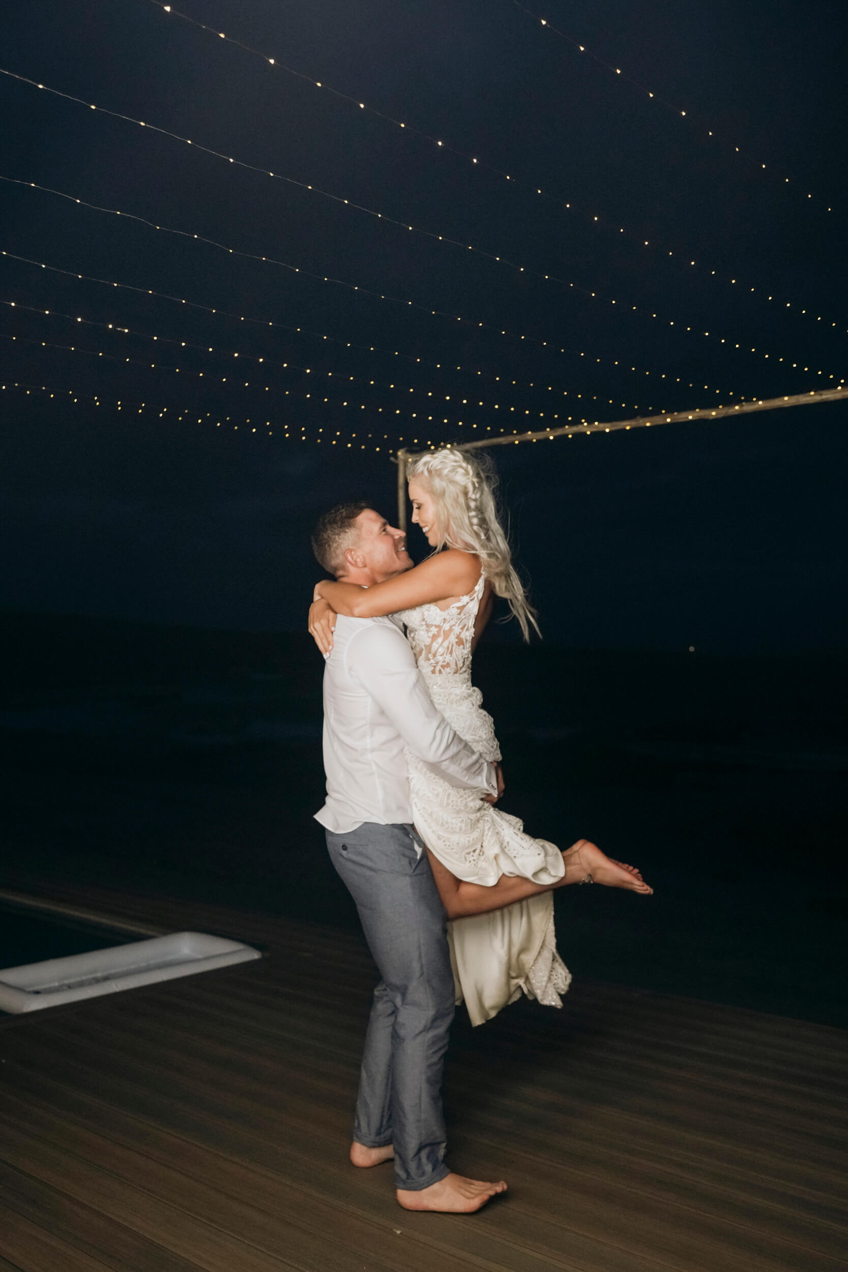 Groom lifting bride on dance floor during wedding reception celebration