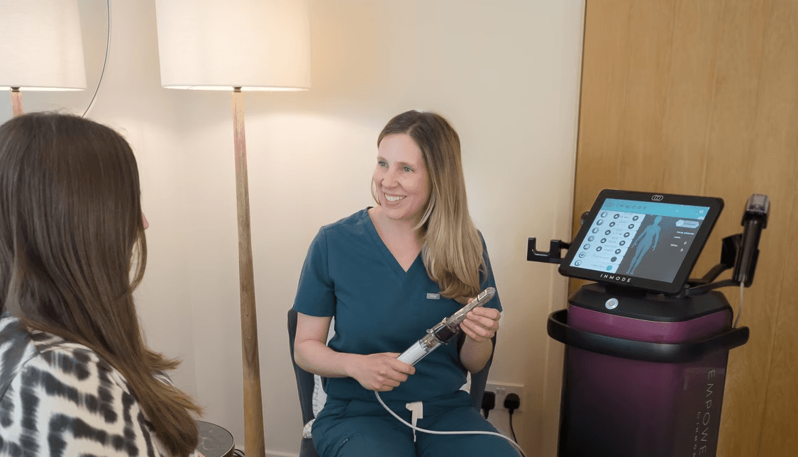 Trish Mueller, founder of Lift and Revive, explaining Morpheus8 V treatment to a female client in the clinic.