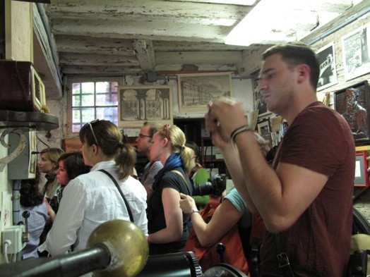 A photo of a group of people sitting in an art workshop.