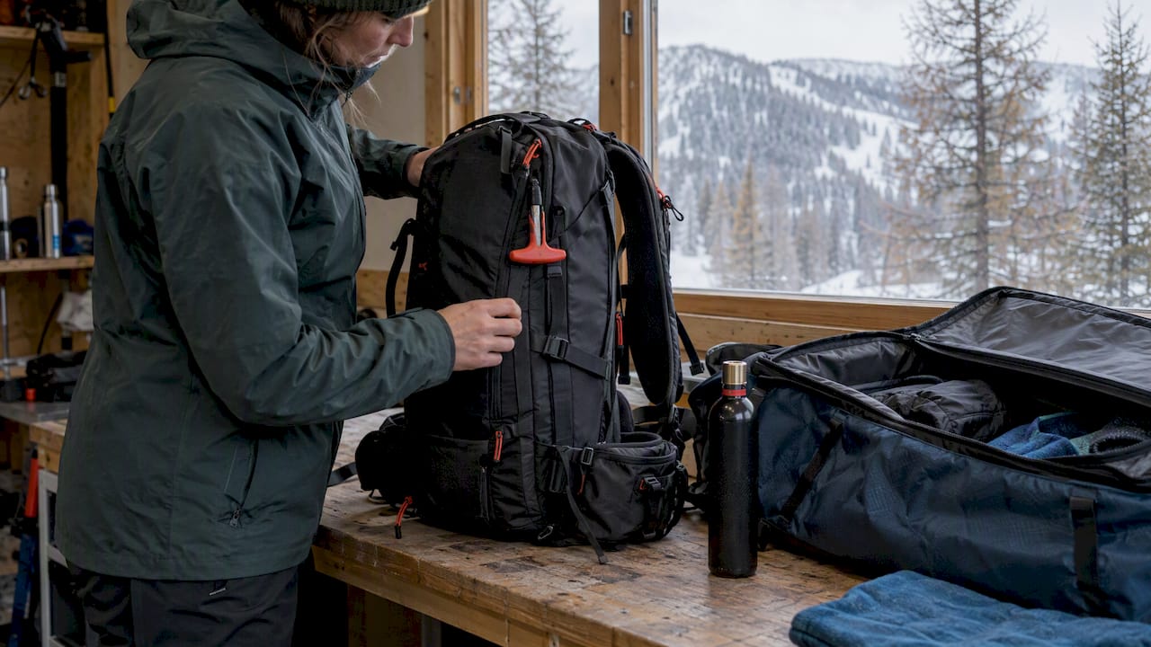 Avalanche airbag backpack beside an open travel bag