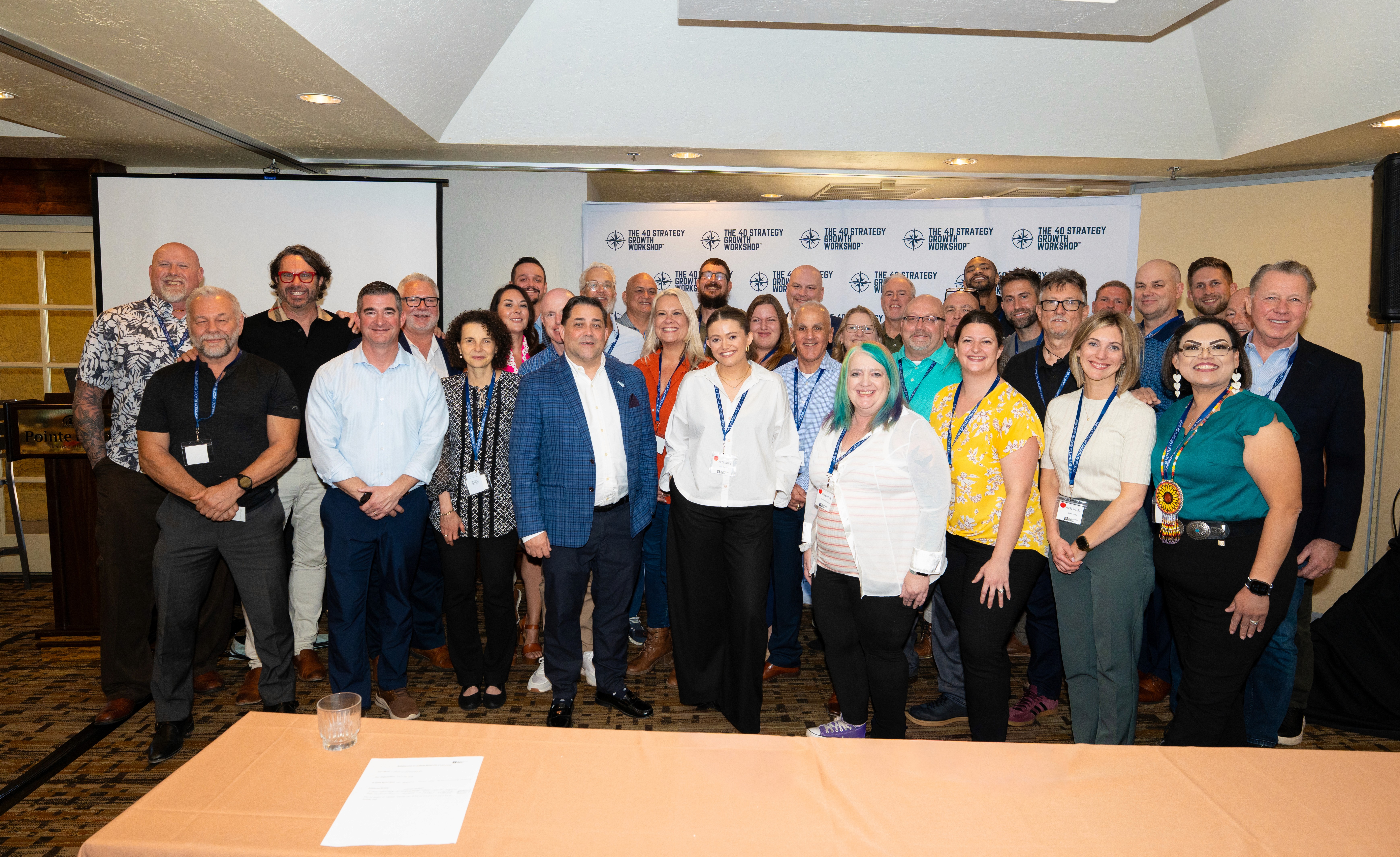A father carries his daughter on his shoulders as she reaches into an open car trunk. They're by a car and some houses.