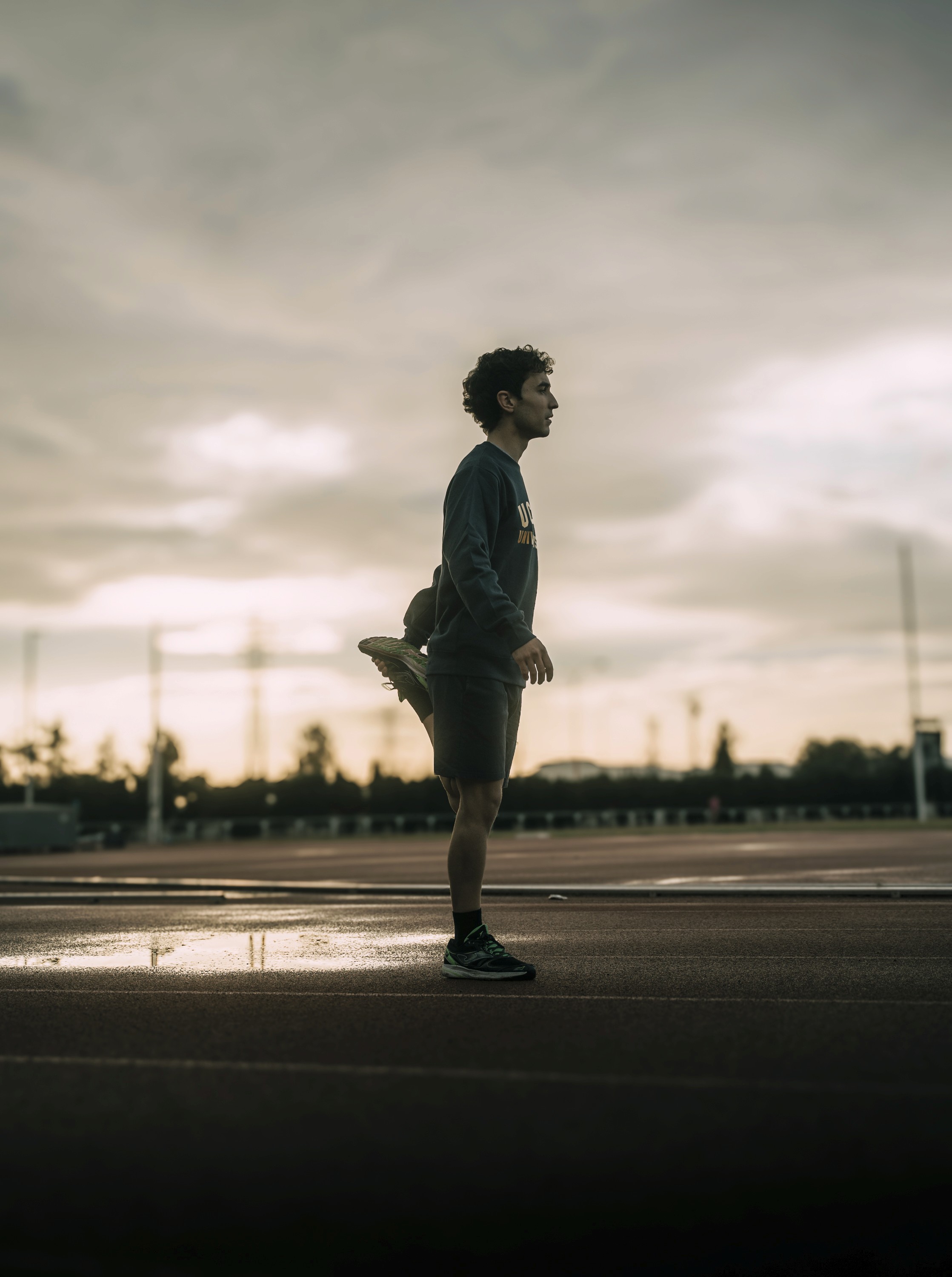 Estudiante UCAM calentando en la pista de atletismo al amanecer – categoría Deporte