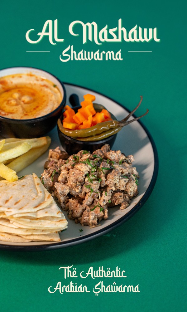 Al Mashawi Shawarma platter with hummus, grilled meat, pickled vegetables, and pita bread on a green plate