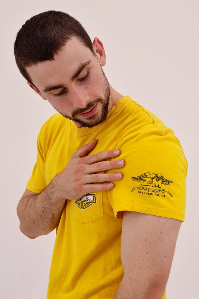 male model wearing yellow shirt, looking at shouler