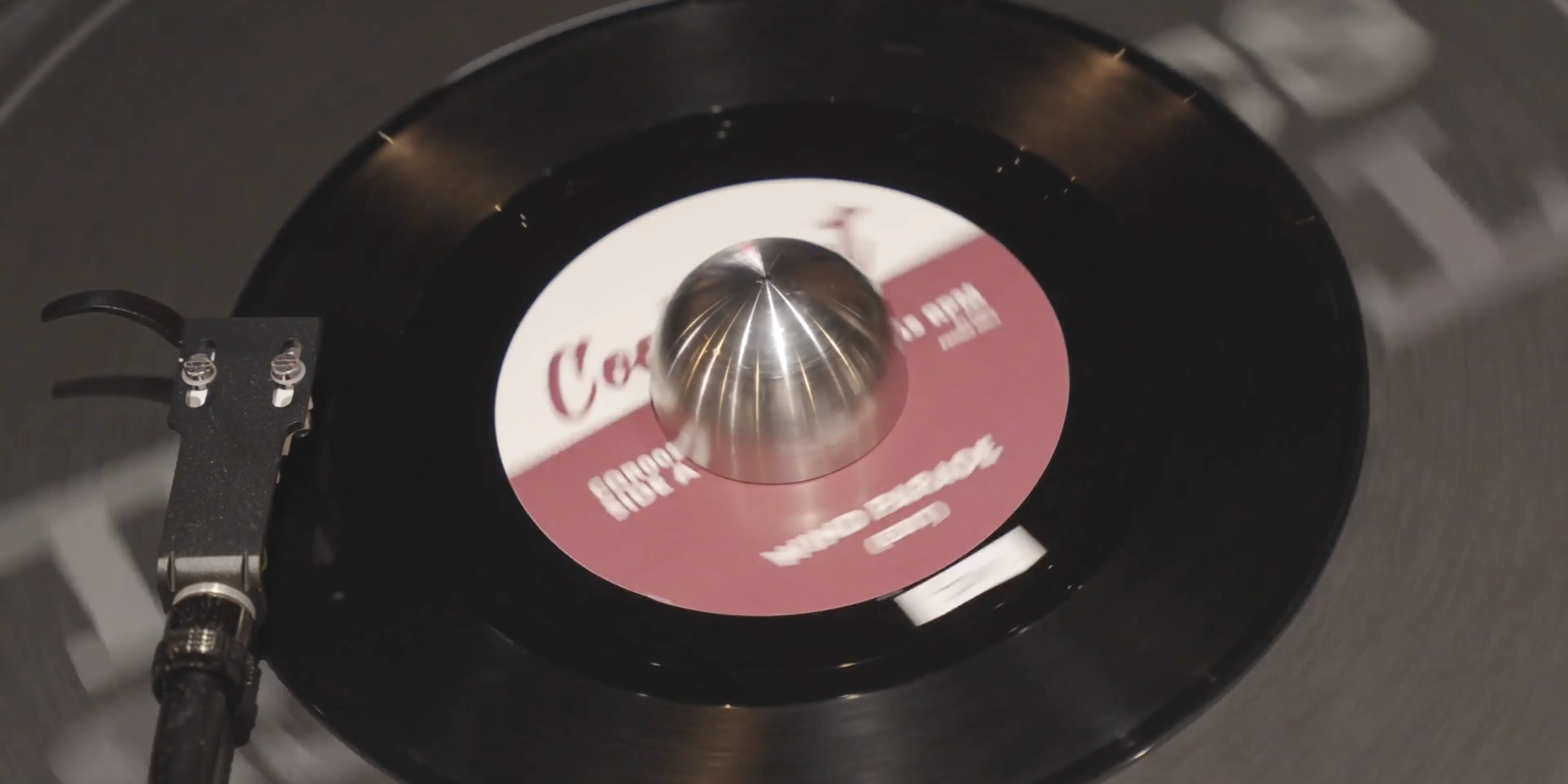 A close-up of a vintage vinyl record spinning on a turntable, featuring a maroon label with white text, capturing the nostalgia of classic music and retro audio equipment.