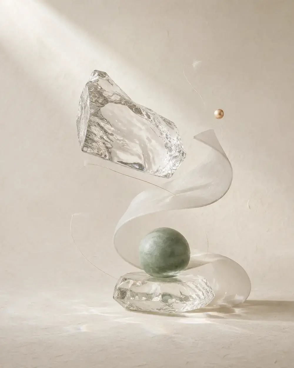 Composición escultórica de vidrio, papel translúcido y una esfera mineral verde sobre un fondo alabastro