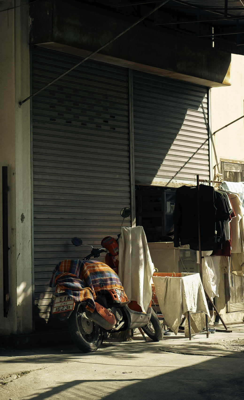 Scooter garé devant une maison dans une rue en Thaïlande, photographie de voyage par Robin Masson