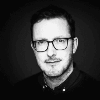 A person wearing glasses and a black shirt.