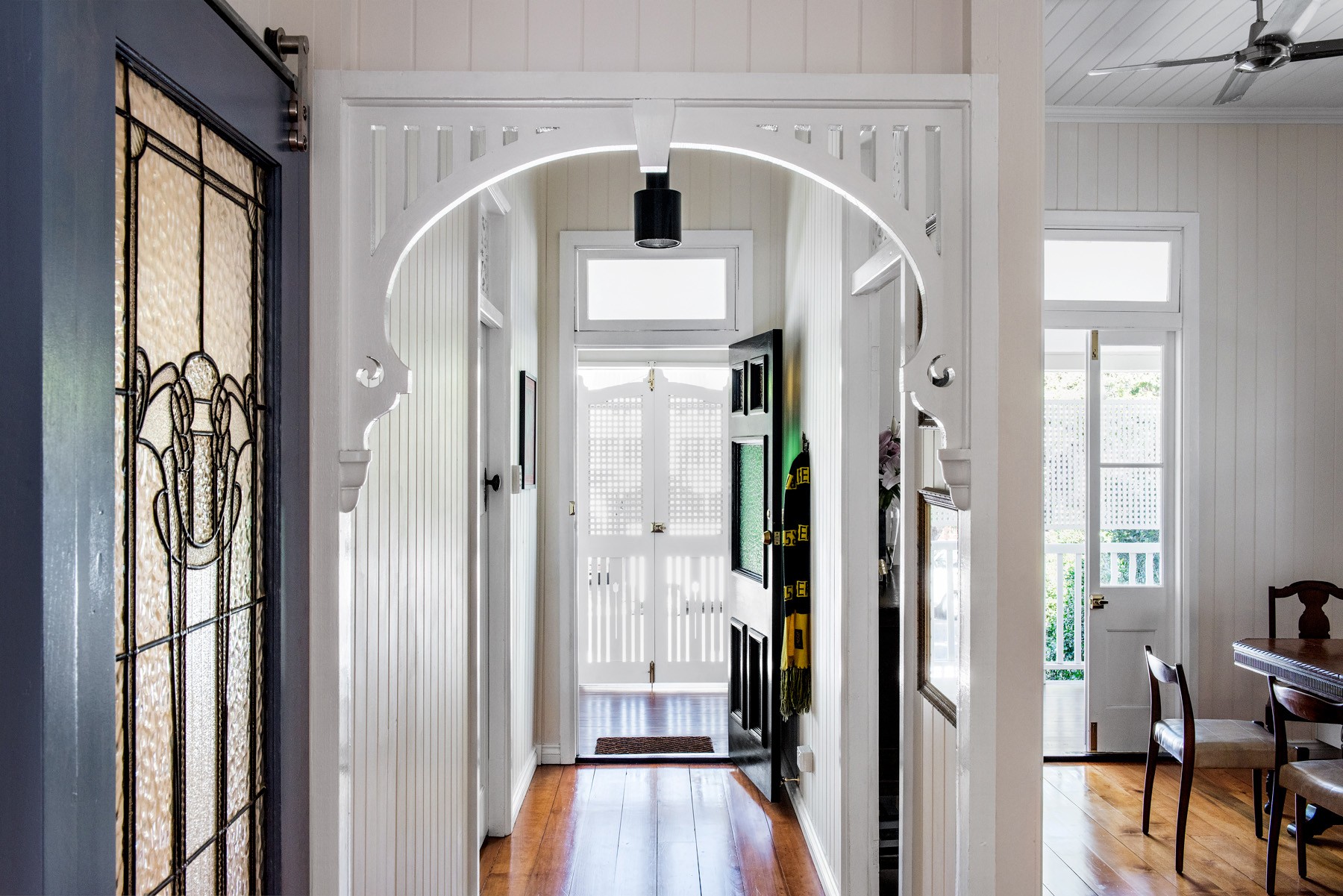 Interior hallway of Oxford Cottage featuring an arched opening, restored timber floors, and layered sightlines through the home.
