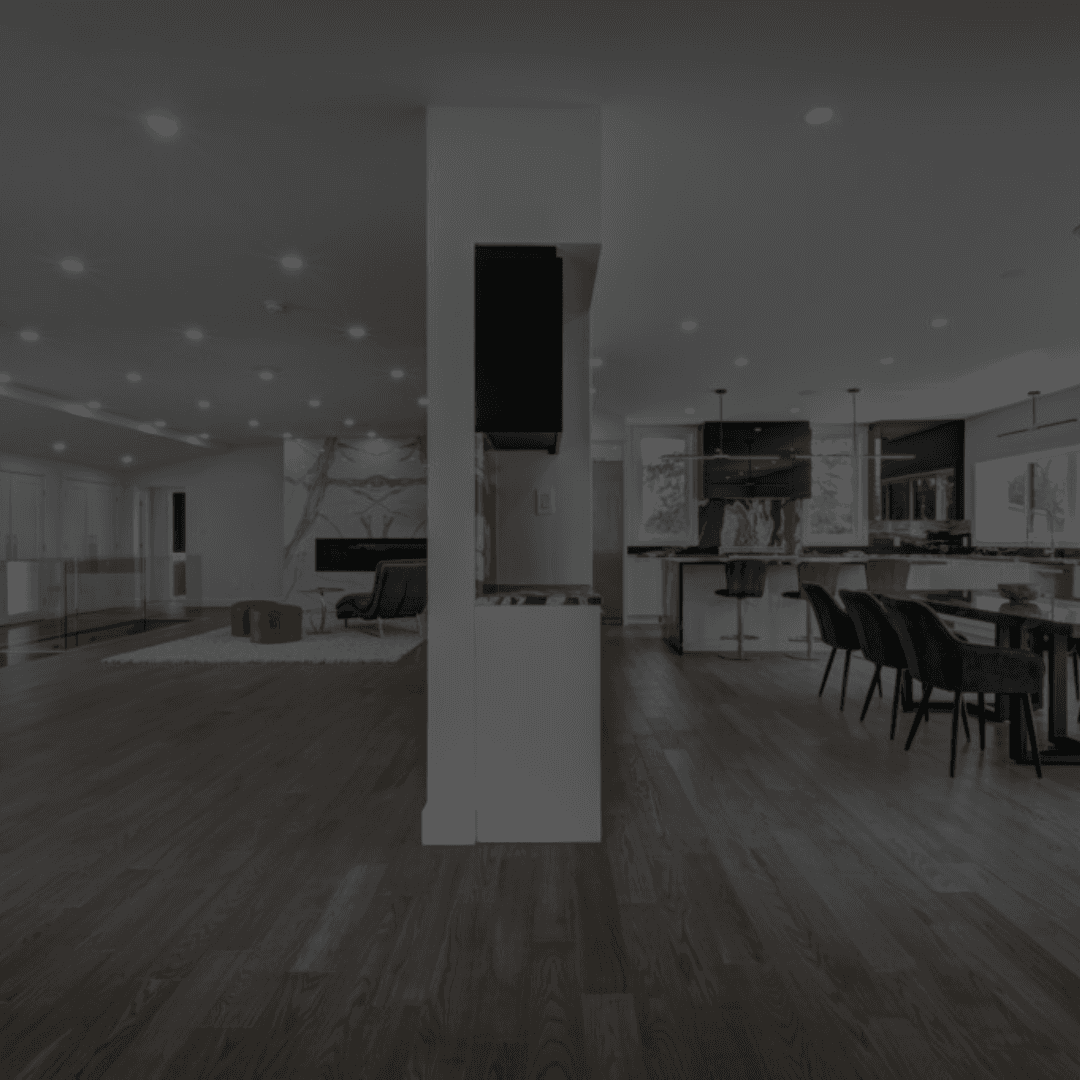 Modern open‑concept living area and kitchen with dark wood flooring, recessed lighting, a large center island with bar stools, and adjacent dining space — showcasing B&Y Reno Corp’s high‑end renovation work