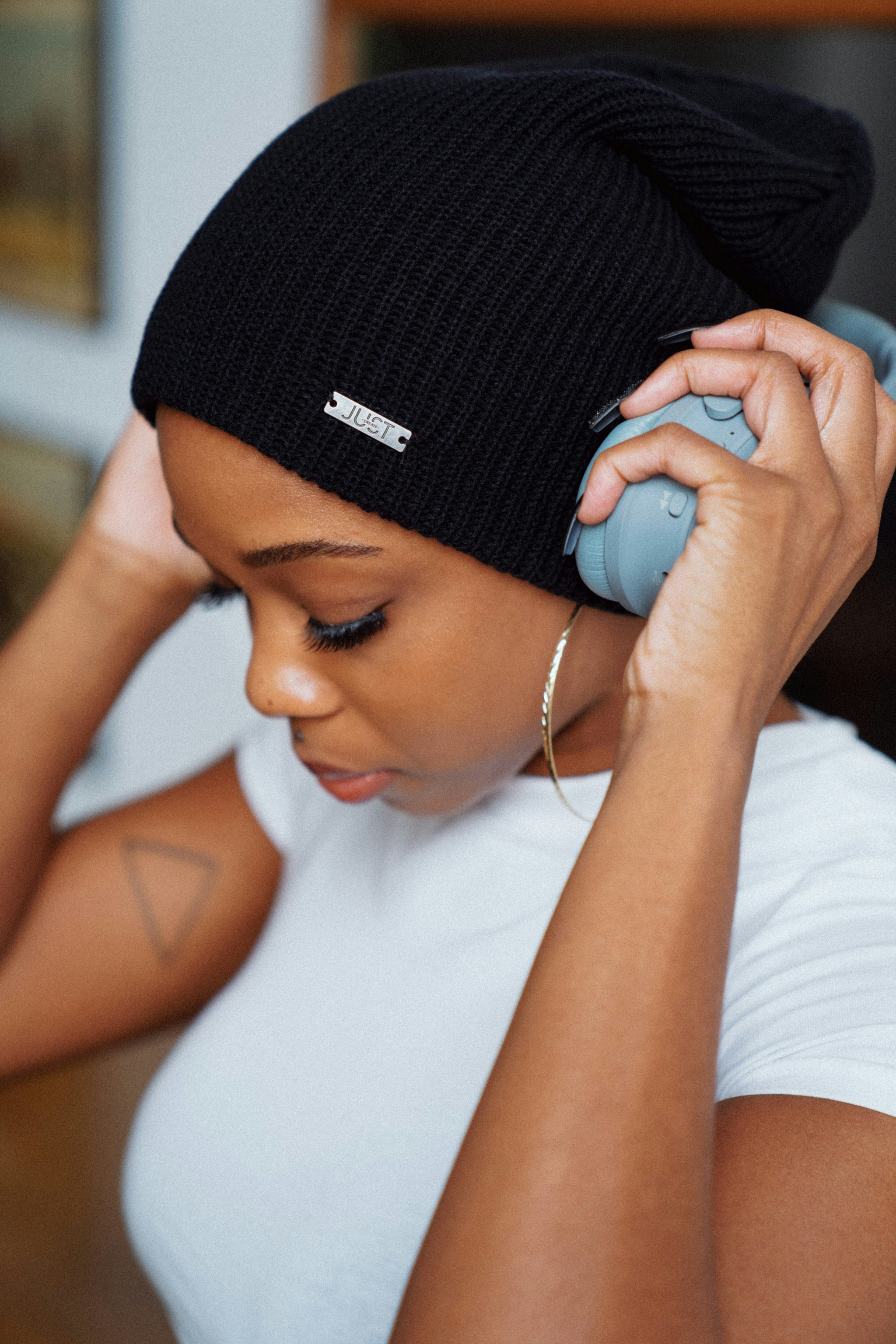 Young woman in a black beanie listens to music with headphones, eyes closed, enjoying the moment.