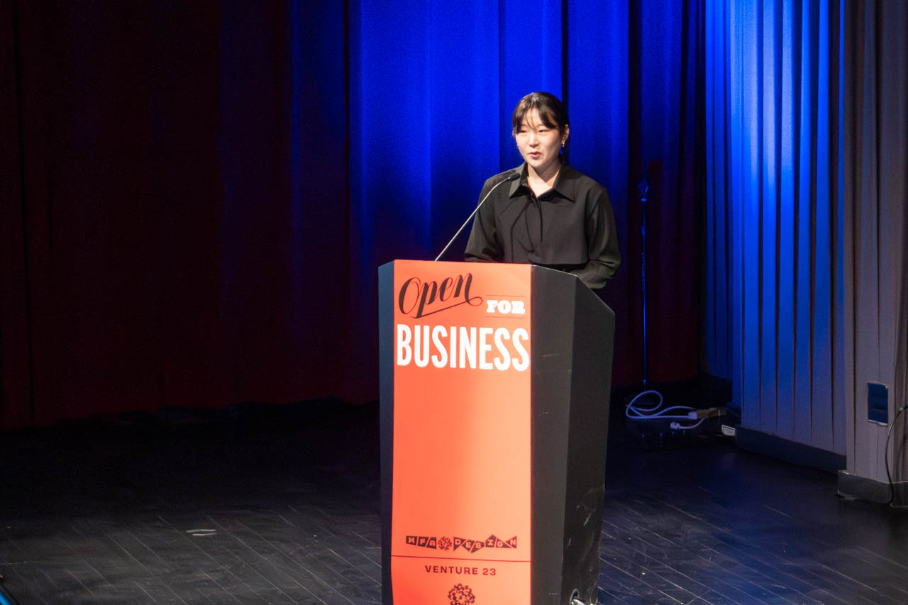 woman standing at a podium delivering a presentation
