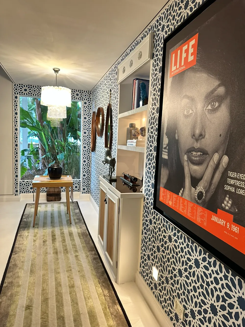 A patterned corridor at Capri Tiberio Palace with a large vintage magazine cover framed on the wall.