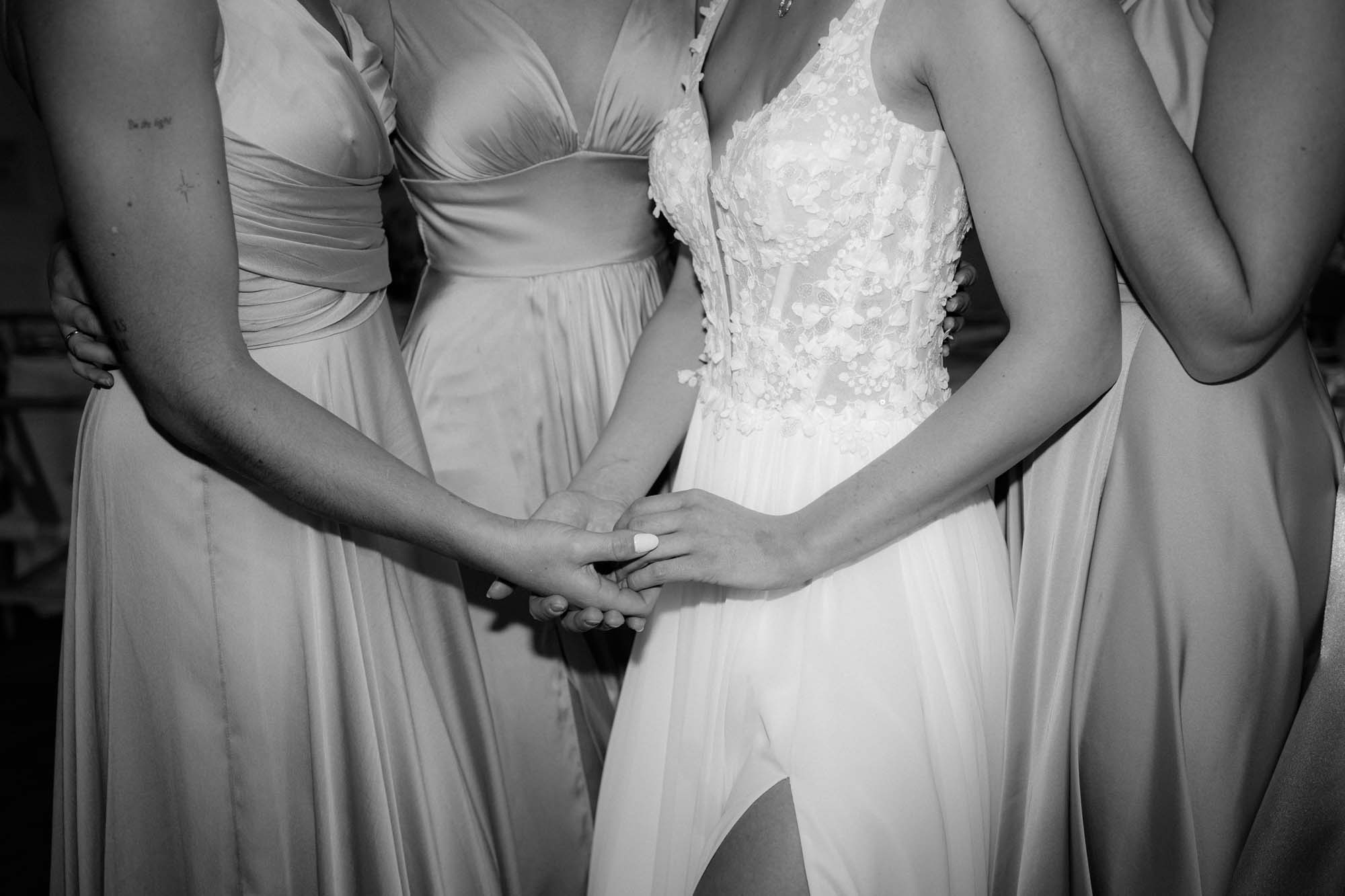 Nahaufnahme von den Händen der Braut mit Brautjungfern und den Kleidern.